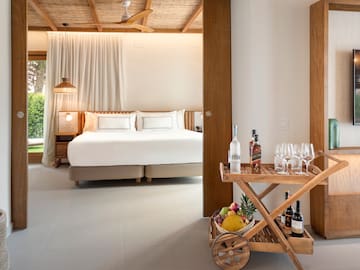 a room with a bed and a cart with wine bottles and glasses