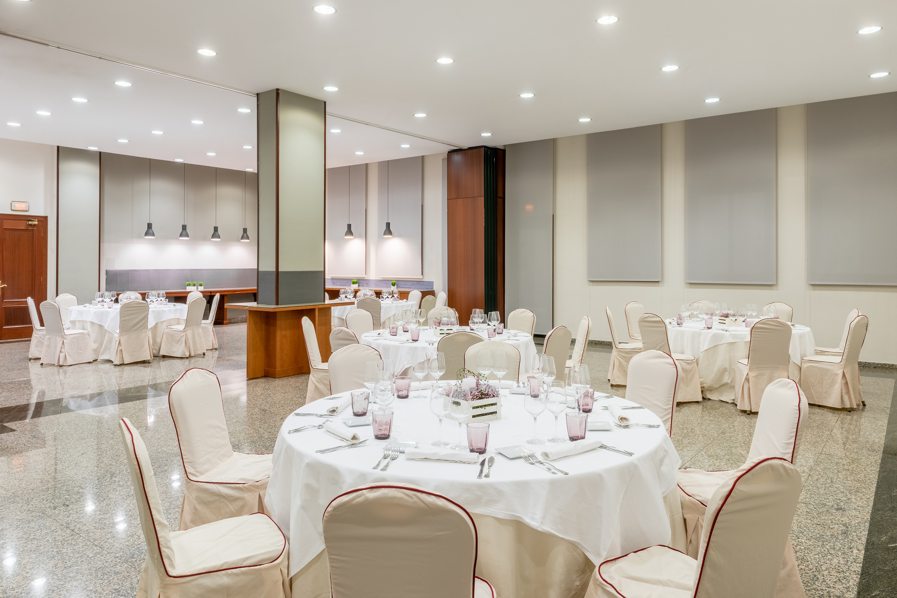 Large, elegant banquet hall set with white covered round tables for events.