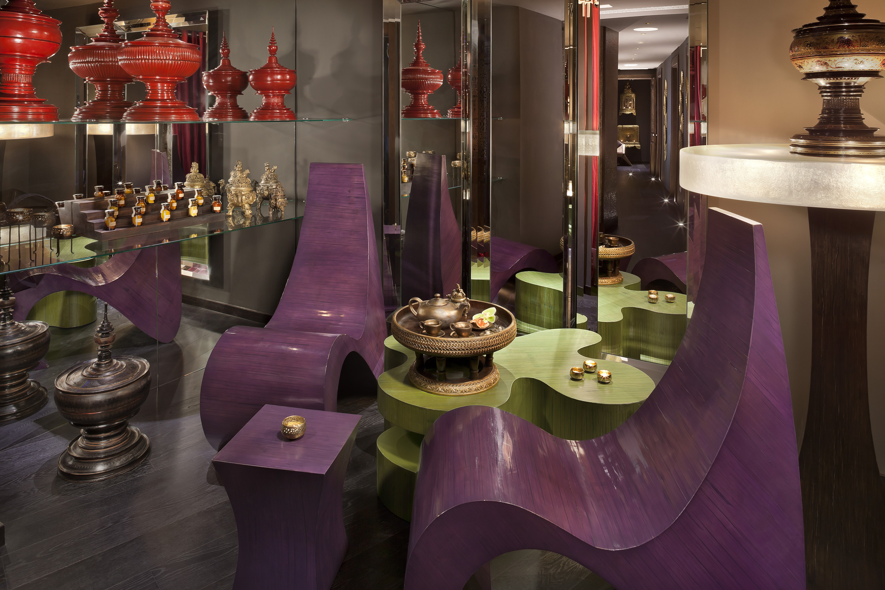 Exotic spa lounge with purple wave chairs, green tables, and traditional Asian decor.