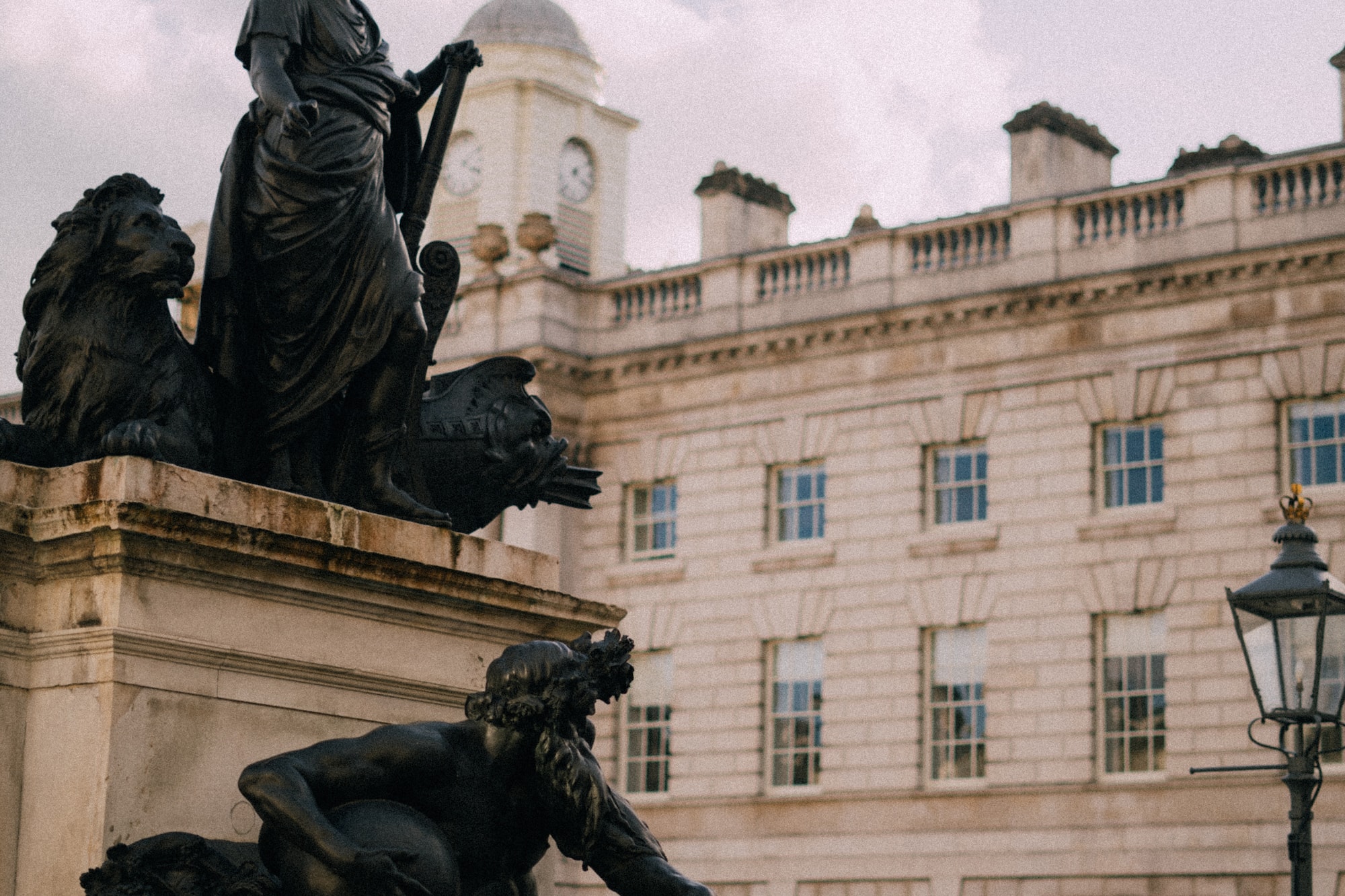 Dark bronze sculptures at King's College London, with a clock tower building.