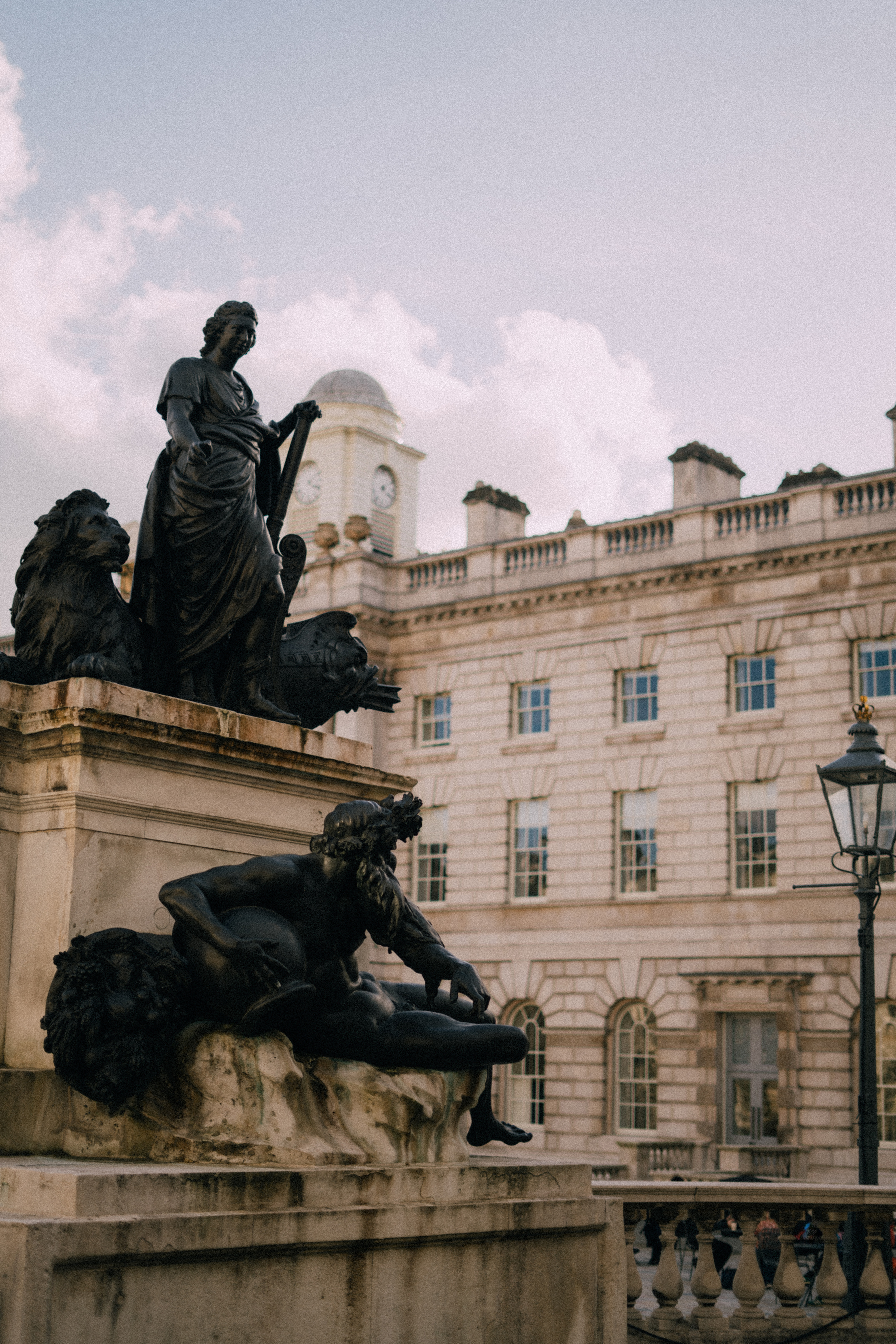 Dark bronze sculptures at King's College London, with a clock tower building.