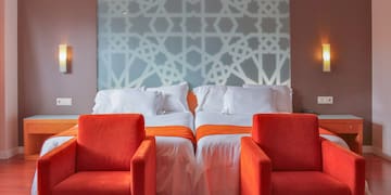 a room with two beds and chairs