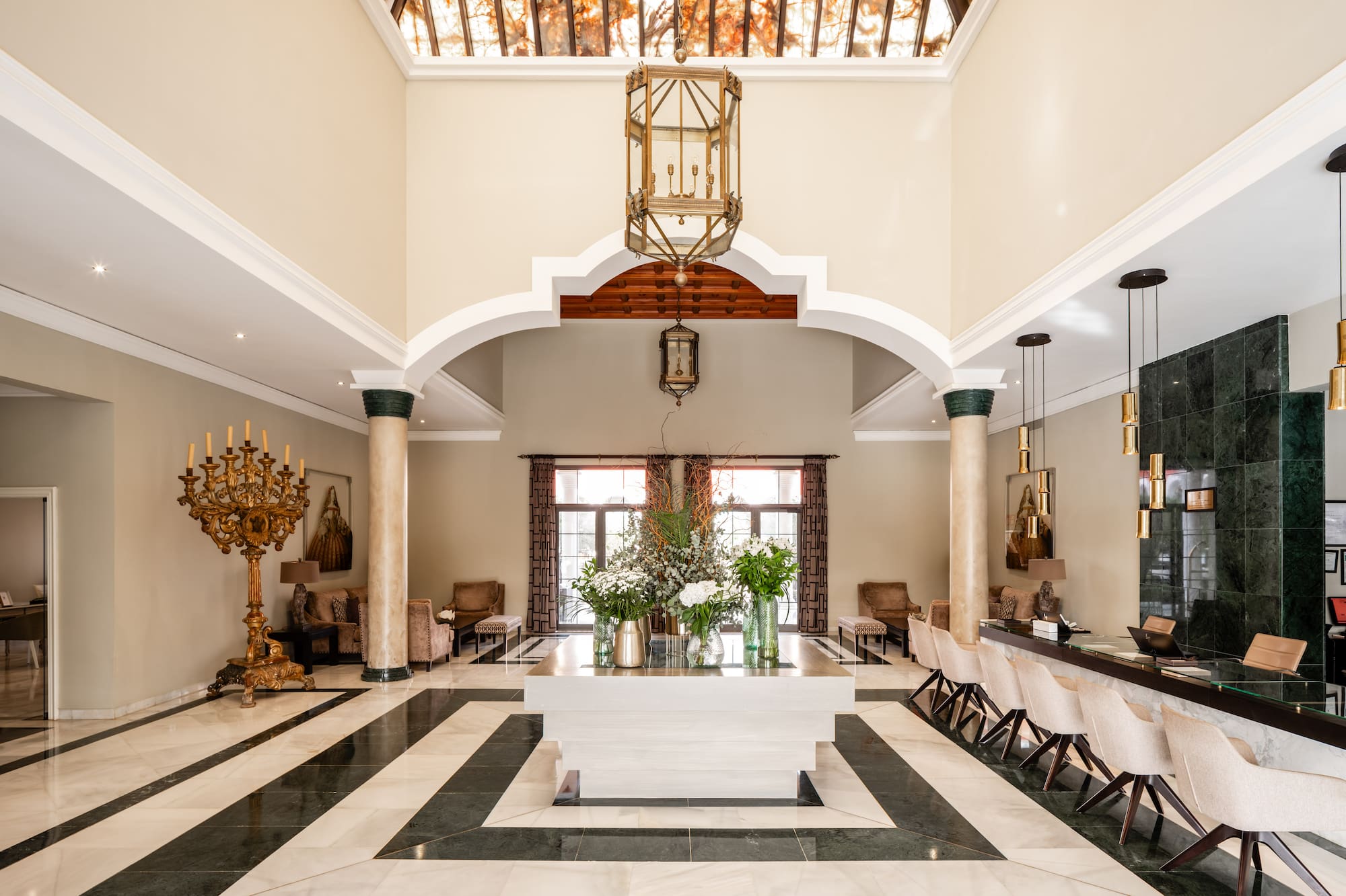 Luxurious hotel lobby with grand chandelier, marble floor, and reception desk.