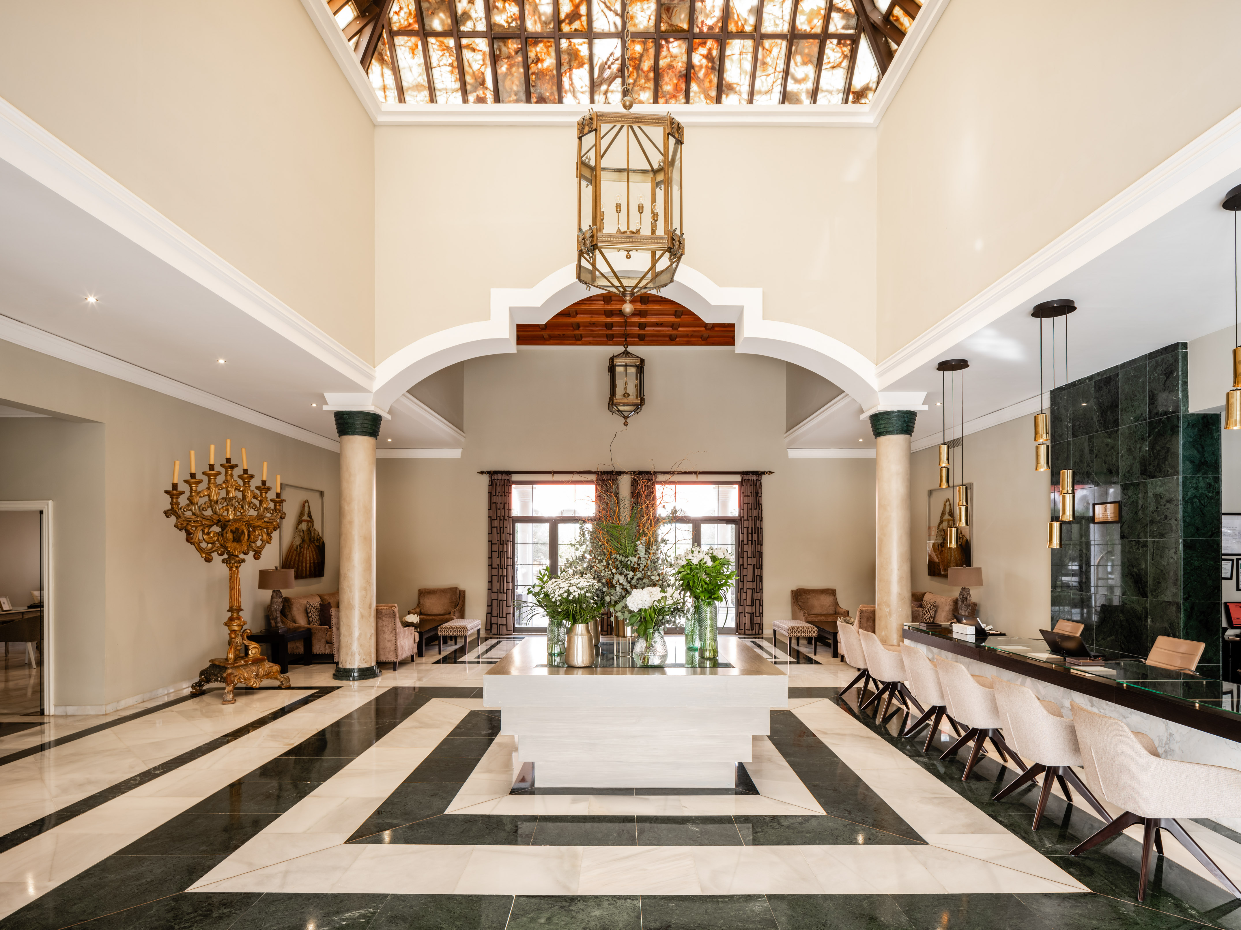 Luxurious hotel lobby with grand chandelier, marble floor, and reception desk.