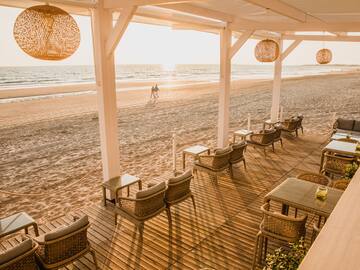 Beachfront terrace with outdoor seating, ocean view, and sunset glow.