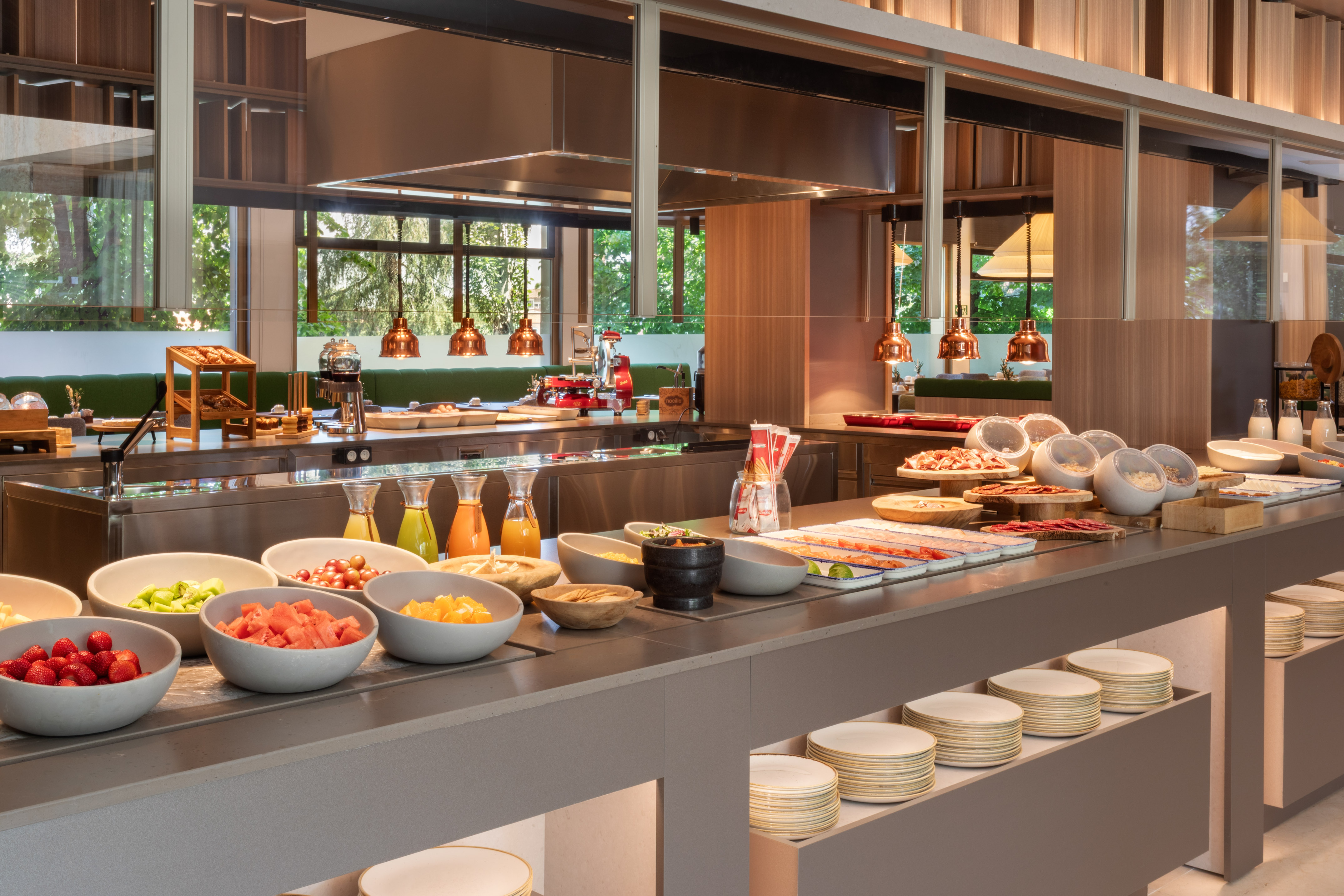 Modern hotel breakfast buffet with fresh fruit, juices, and cold cuts.
