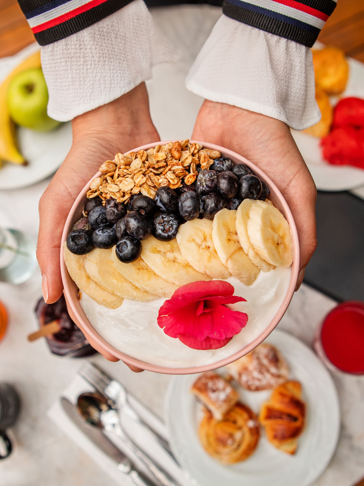 a person holding a bowl of fruit and yogurt