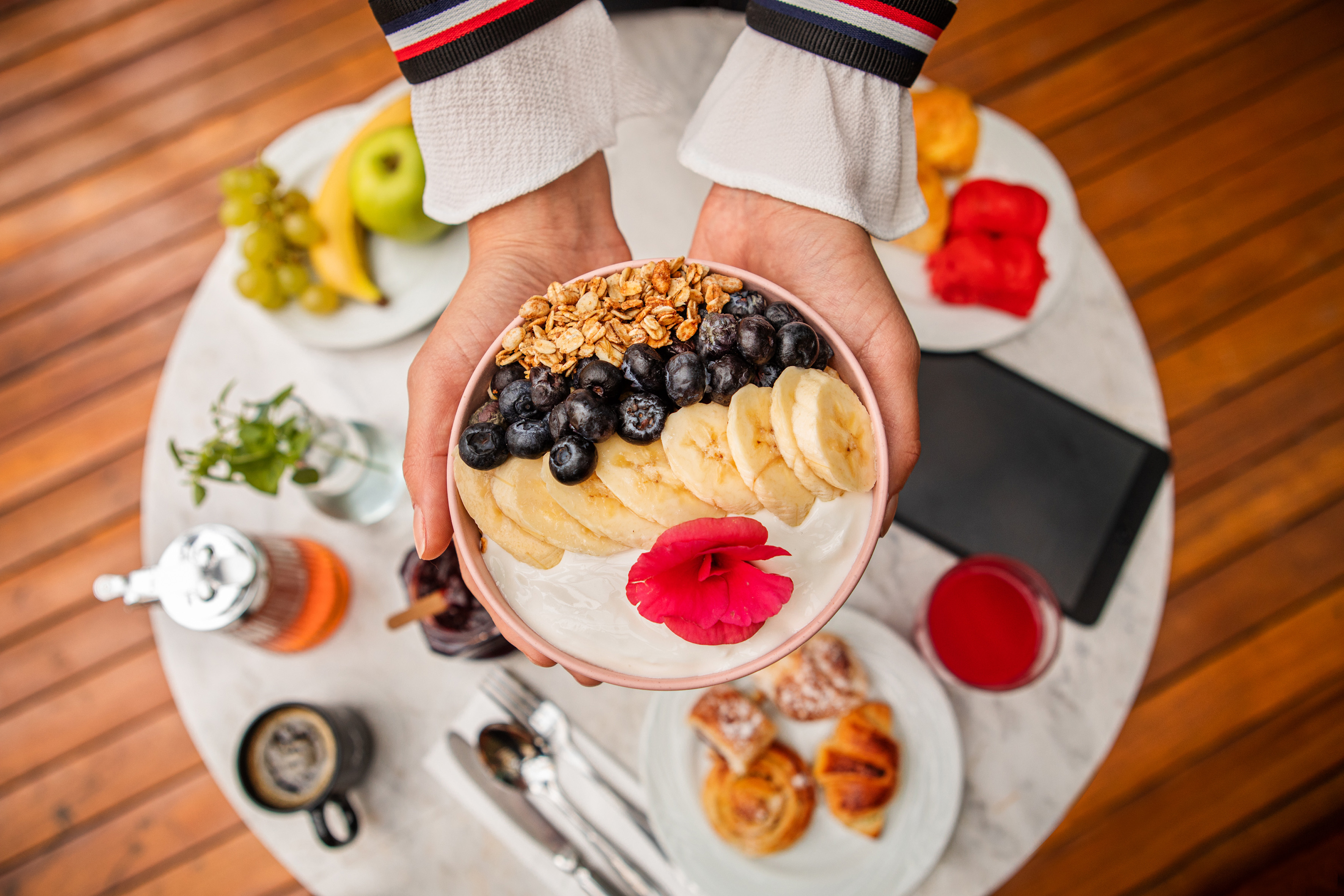 a person holding a bowl of fruit and yogurt