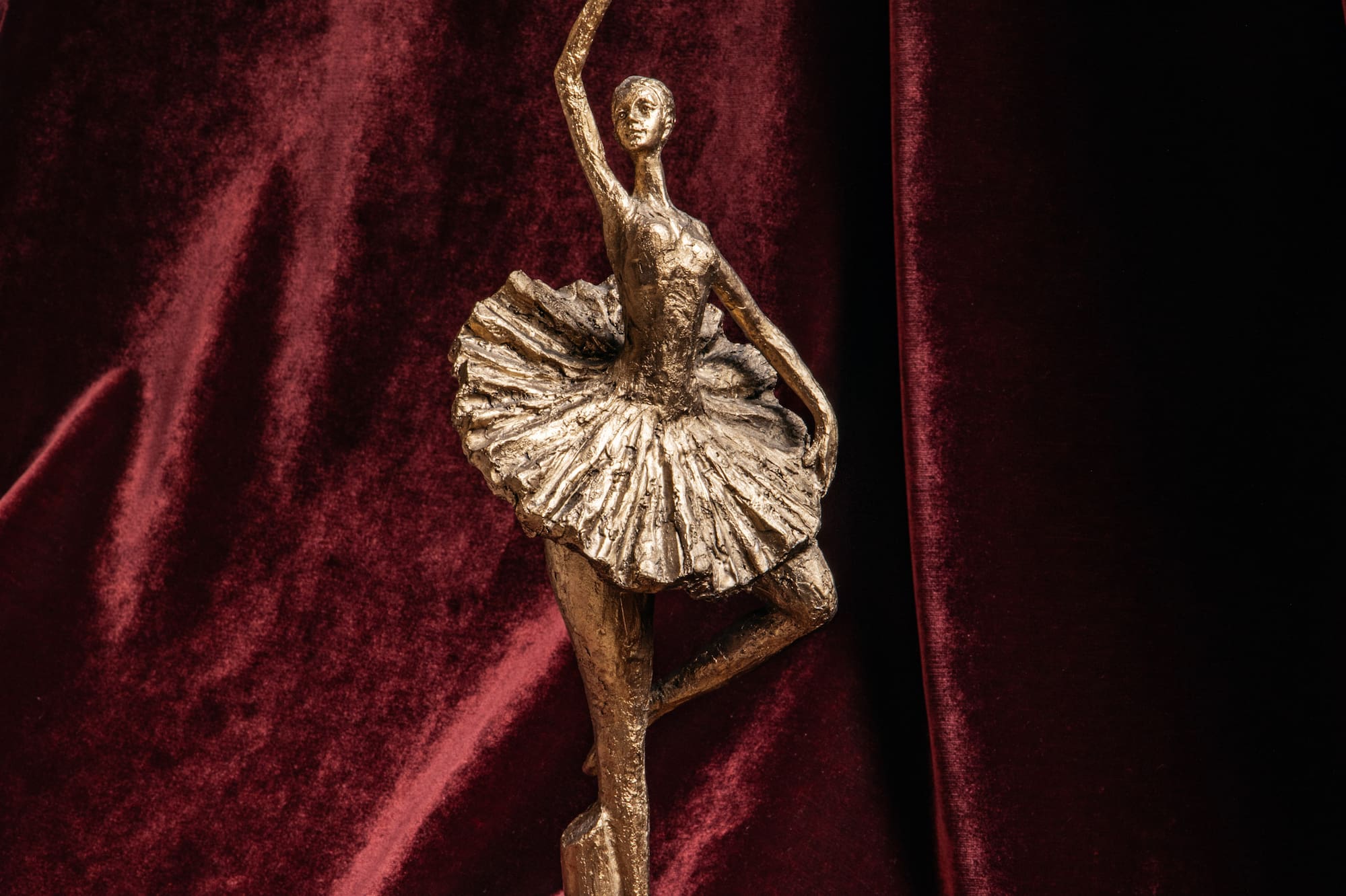 A ballerina statue set against a red velvet backdrop.