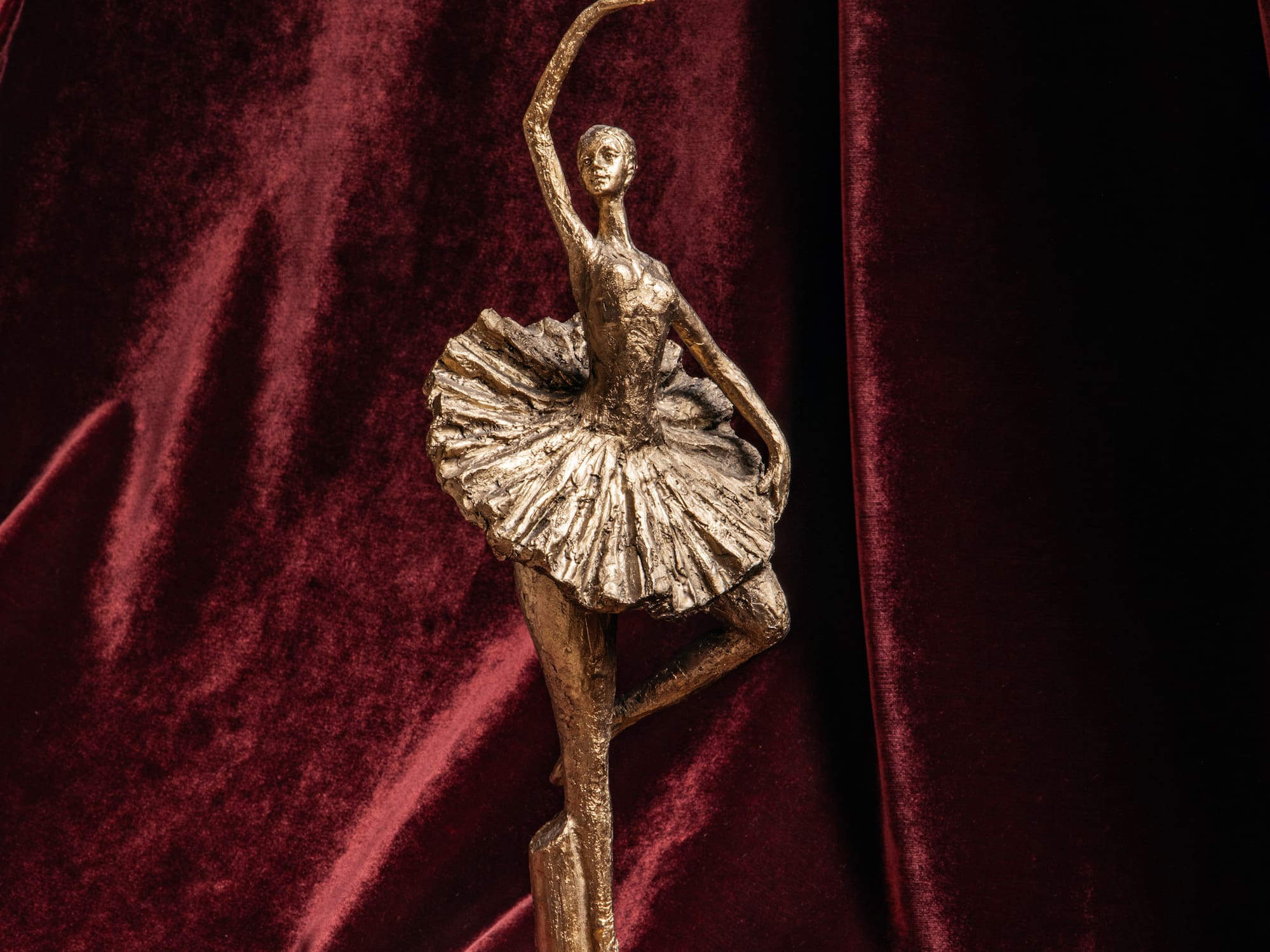 A ballerina statue against a red velvet backdrop.