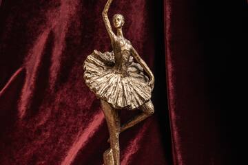 a statue of a ballerina on a red velvet background