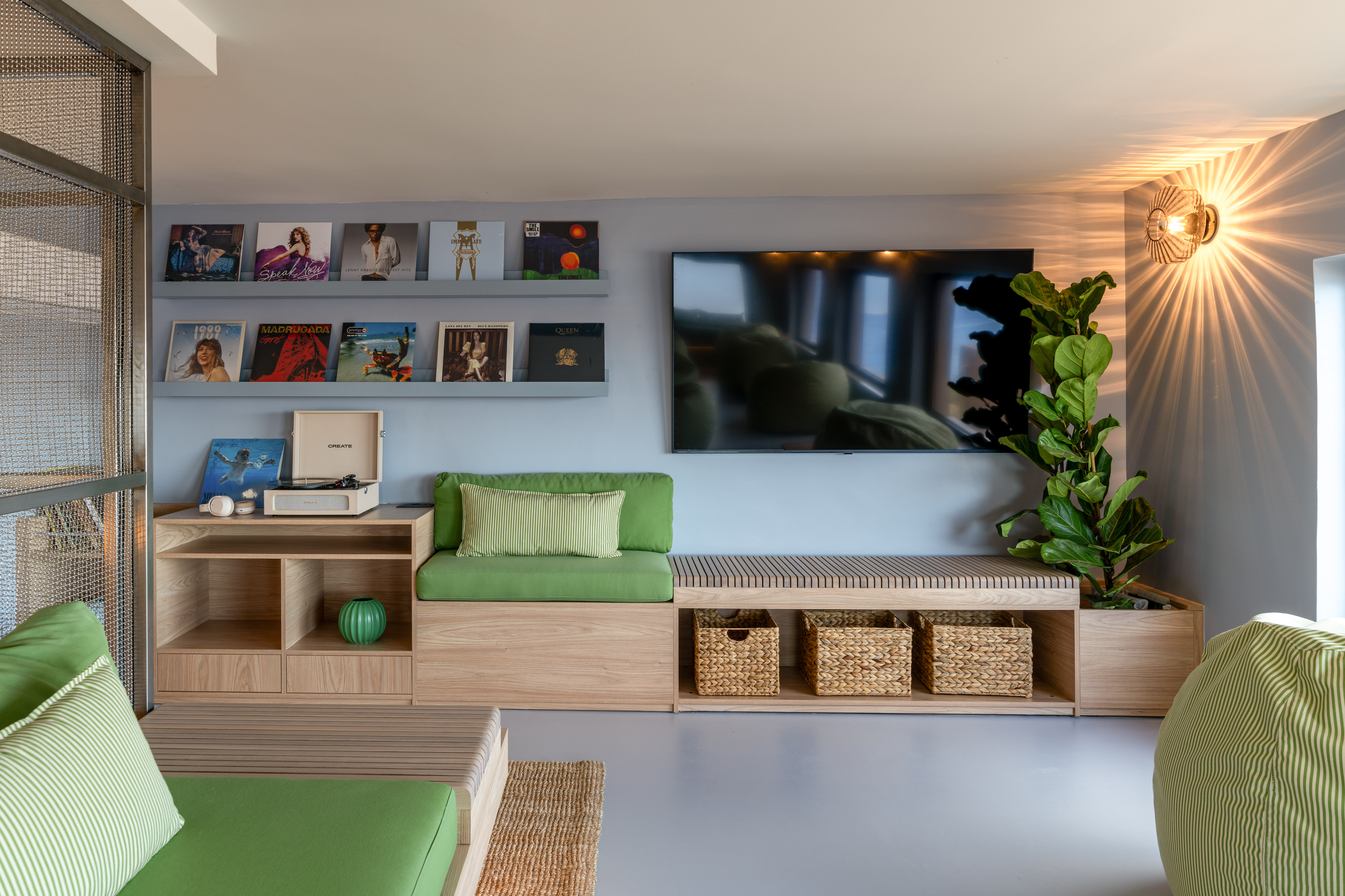 Modern living room: wood bench seating, green cushions, vinyl collection, TV.