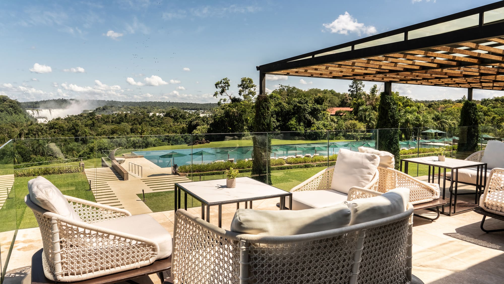 a patio with chairs and a pool in the background
