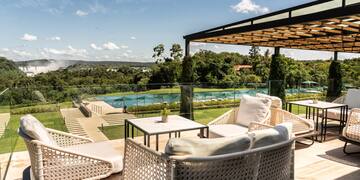 a patio with chairs and a pool in the background