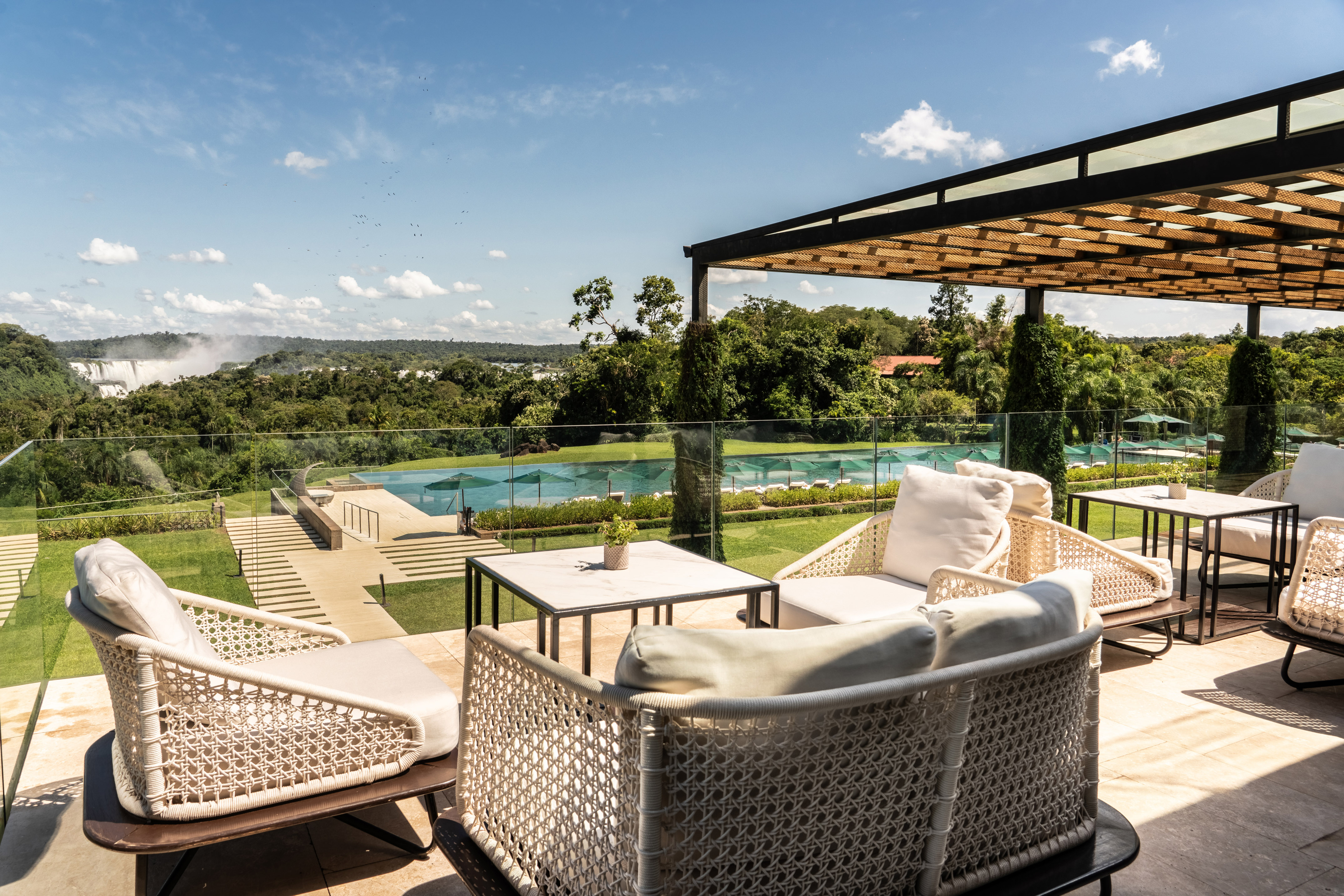 Luxury resort patio with modern seating overlooking waterfall and pool.