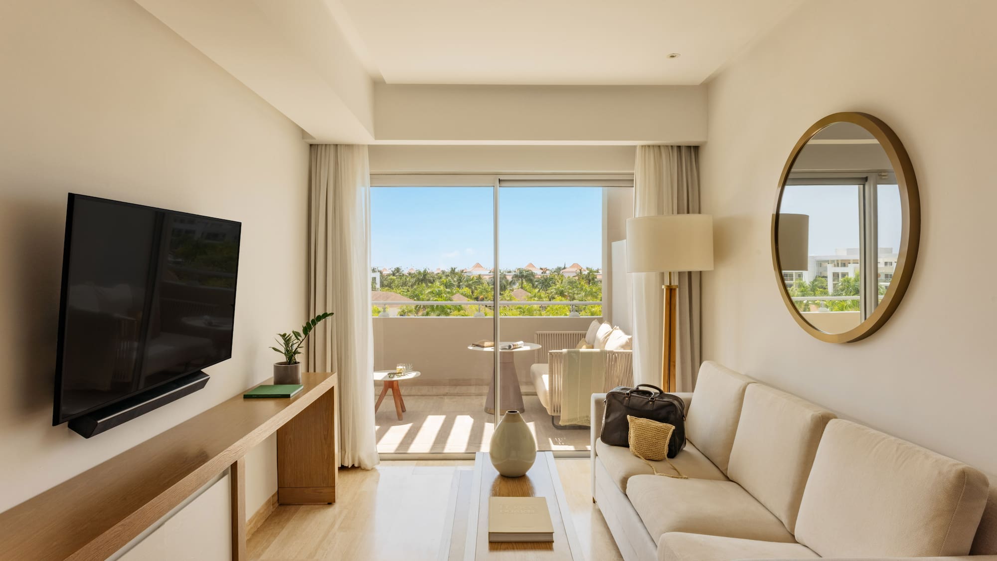 Bright resort suite living room with sofa, balcony, and tropical views.