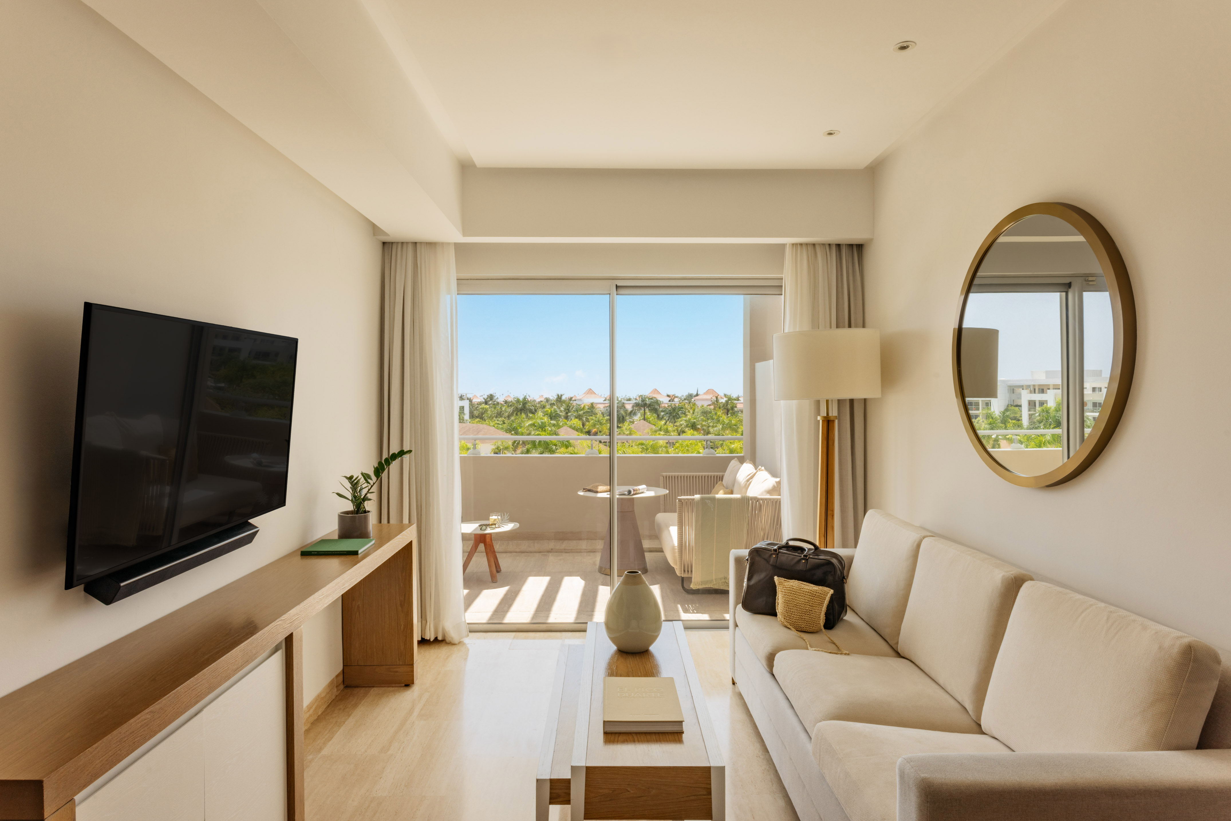 Bright resort suite living room with sofa, balcony, and tropical views.