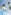 Surfer jumping on Flowrider wave simulator, palm trees, blue sky.
