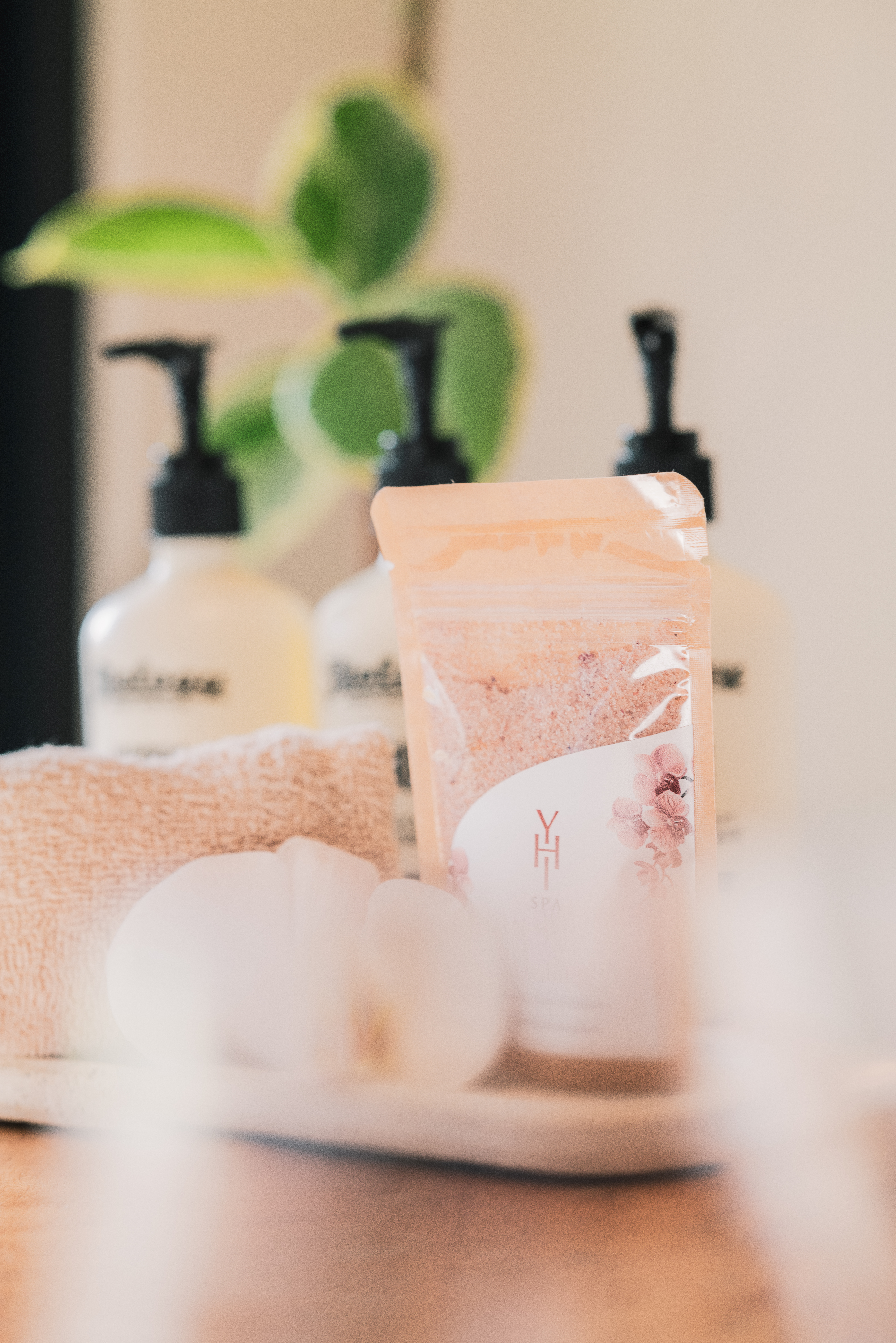 Pink bath salts pouch, spa lotion bottles, towel, and orchids for relaxation.