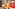Couple smiling, playing colorful board game indoors, small dog resting.