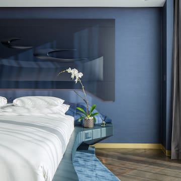 a bed with white sheets and pillows in a room with blue walls