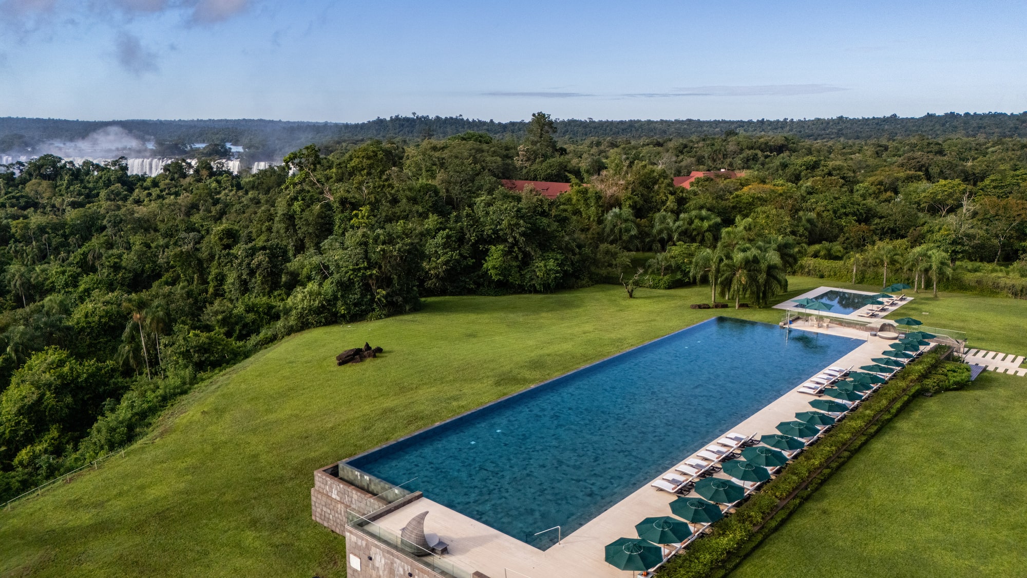 a pool with umbrellas and chairs in a grassy area