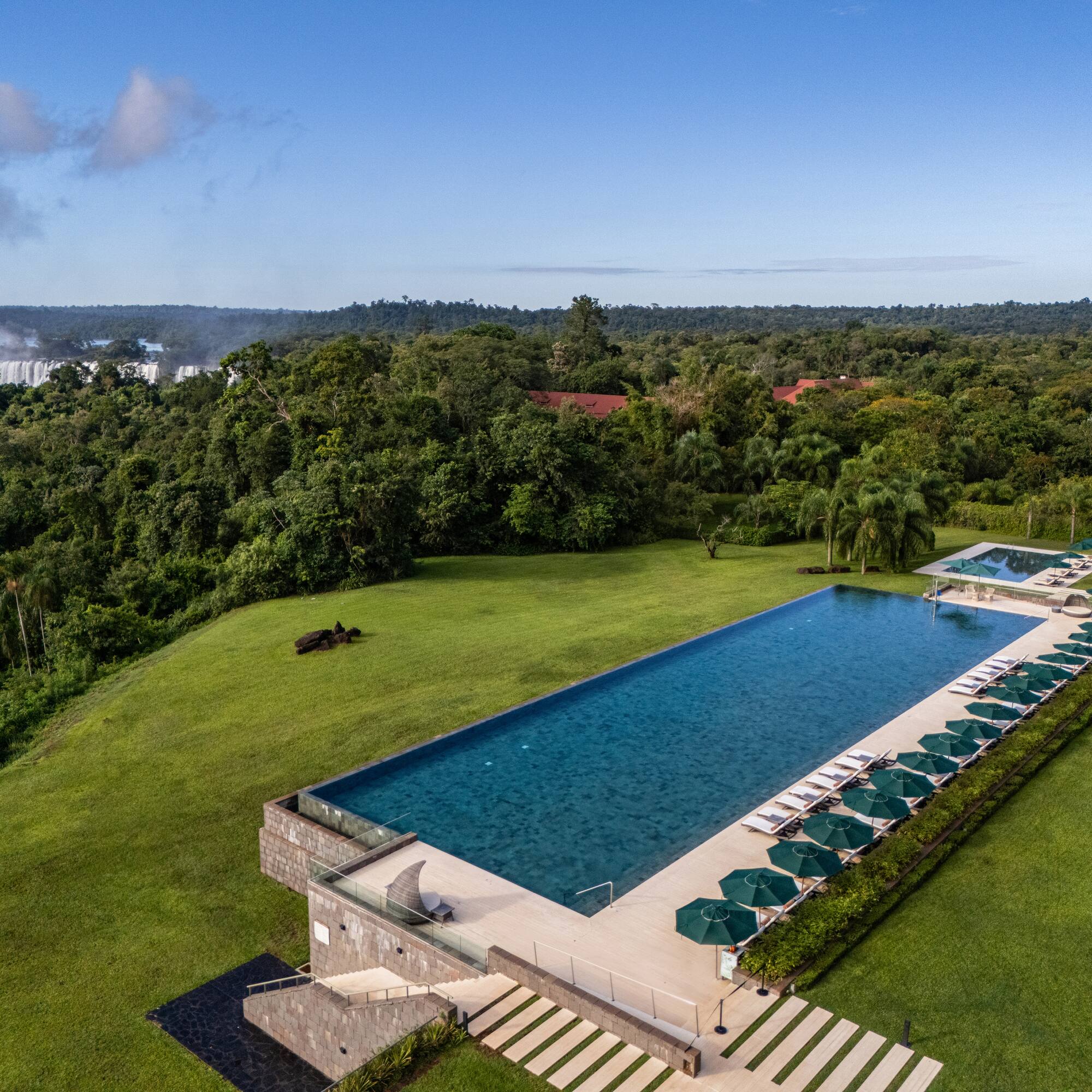 a pool with umbrellas and chairs in a grassy area