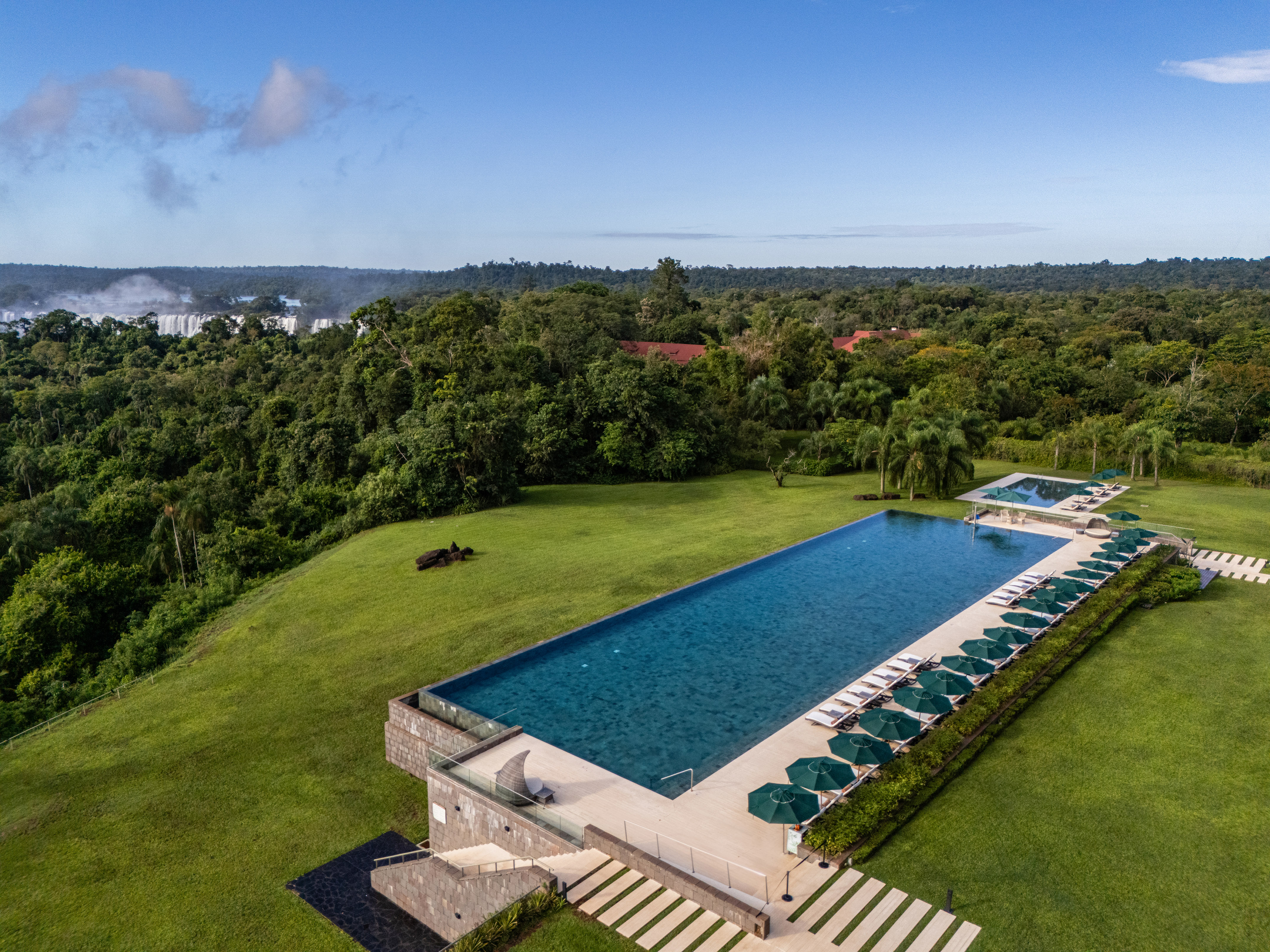 Resort infinity pool overlooking rainforest and distant Iguazu Falls.