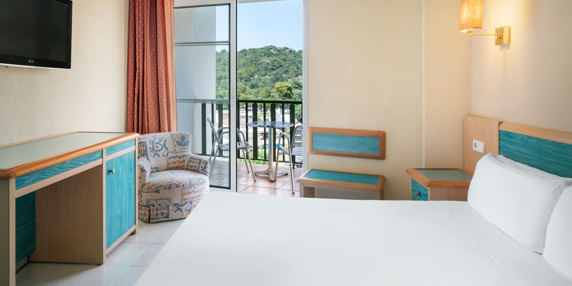 a room with a bed and a chair and a balcony