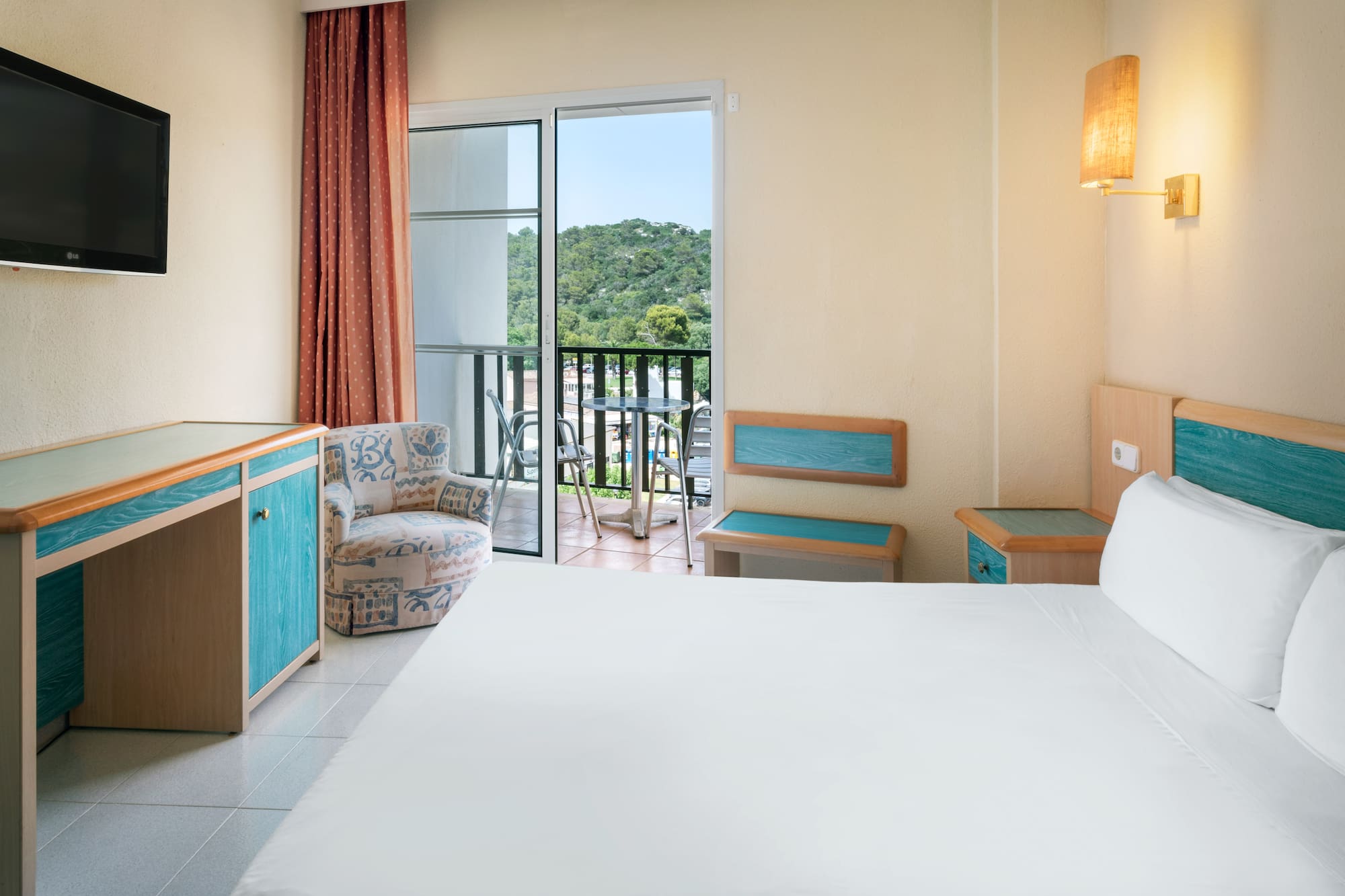 a room with a bed and a chair and a balcony