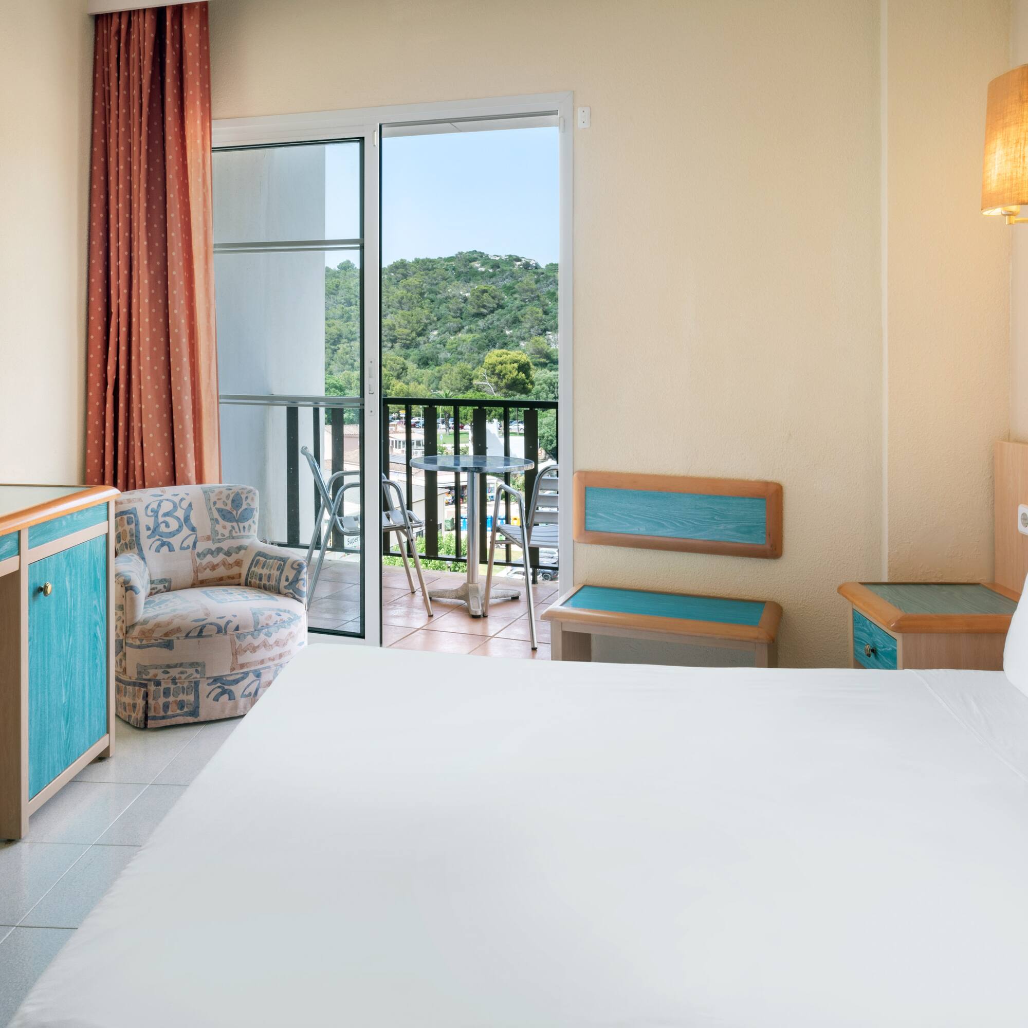 a room with a bed and a chair and a balcony