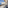 Hotel balcony with sea view, black railing, outdoor seating, beach, blue sky.