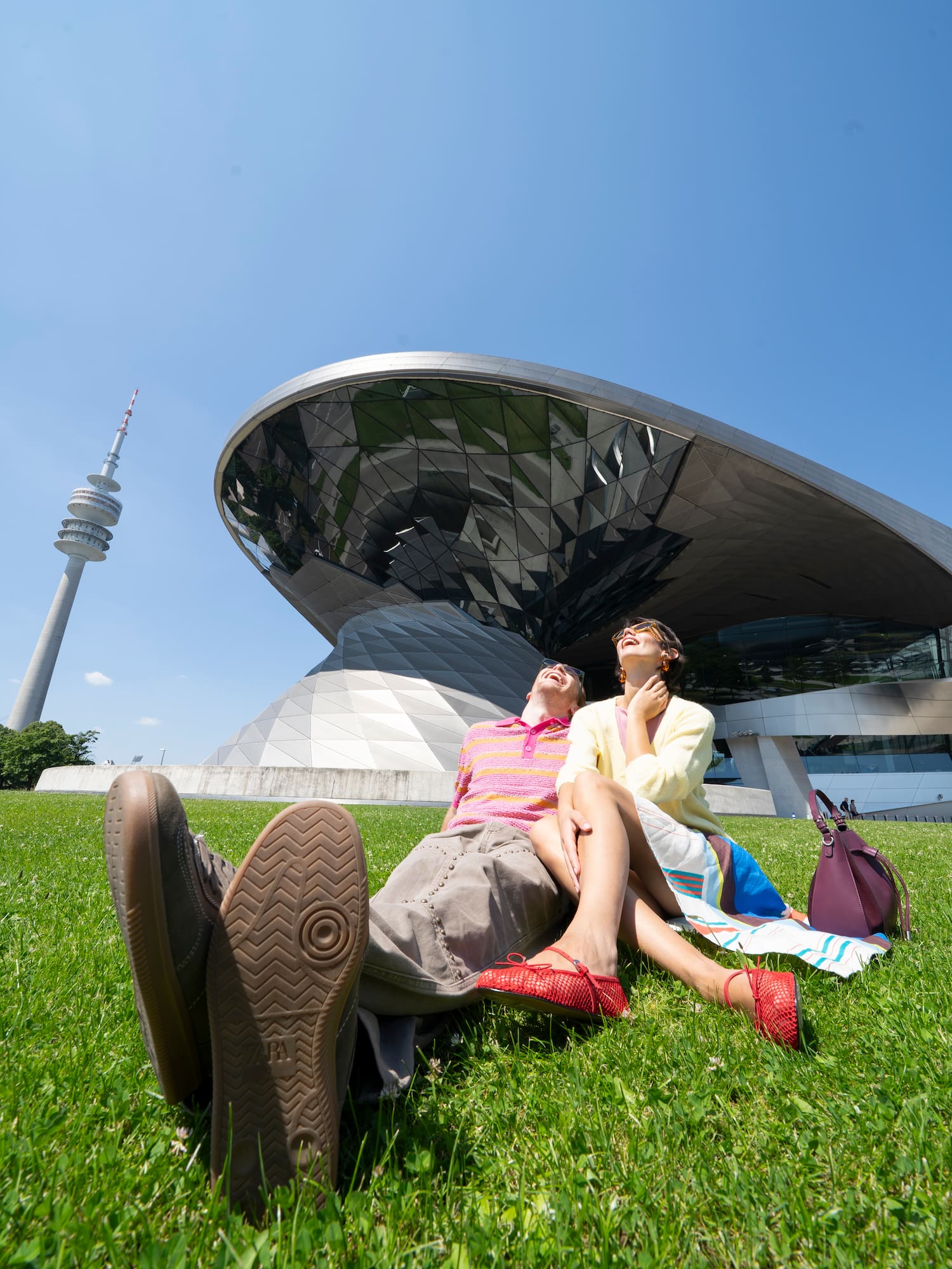 a couple of people sitting on grass in front of a building