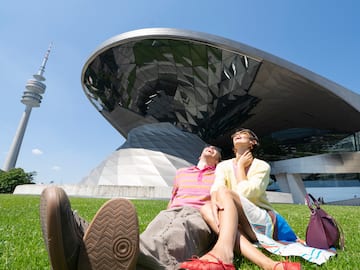 a couple of people sitting on grass in front of a building
