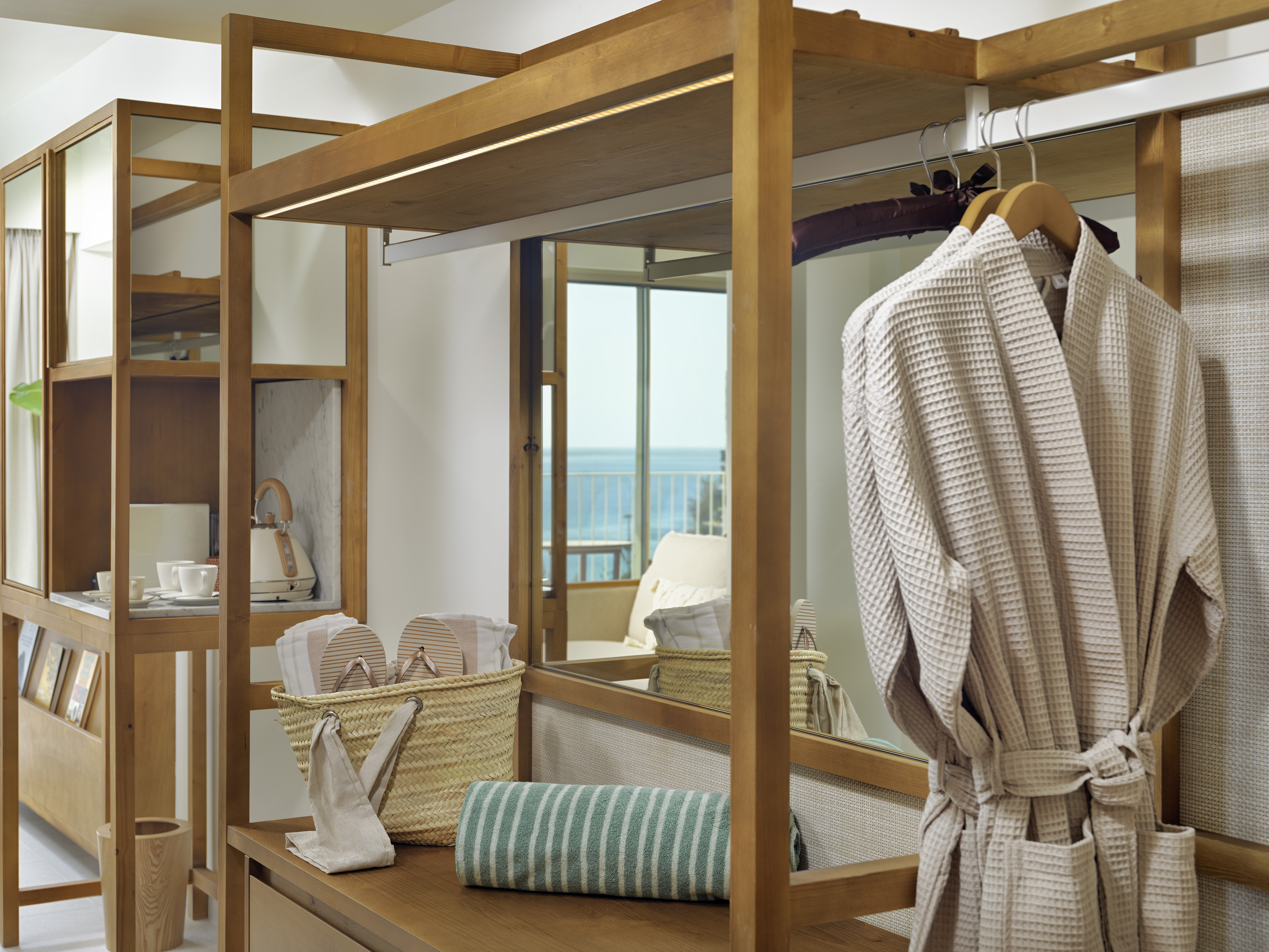Wooden hotel wardrobe with bathrobe, flip-flops, towels, and ocean view.
