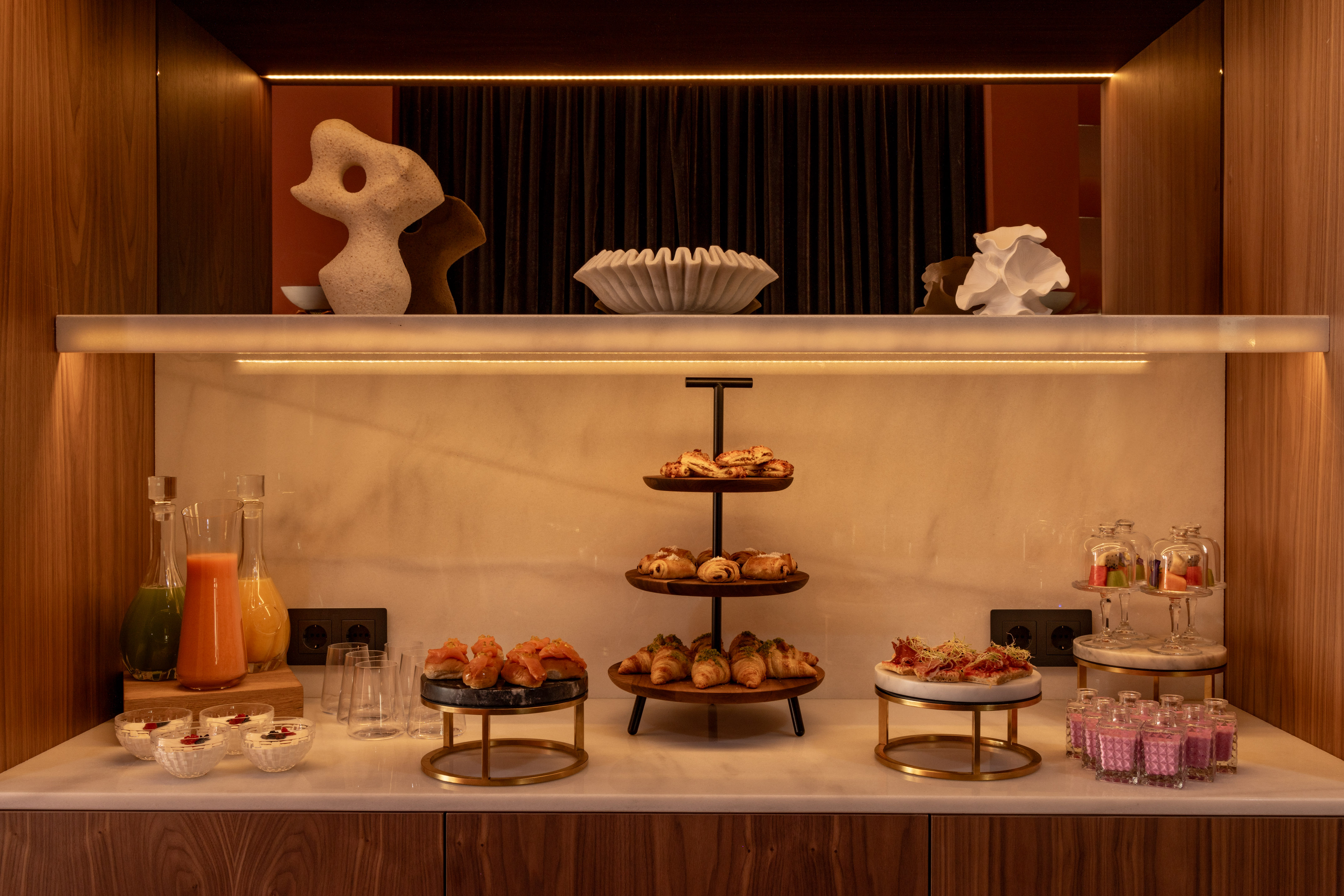 Modern breakfast buffet with croissants, juices, fruit, and savory bites.