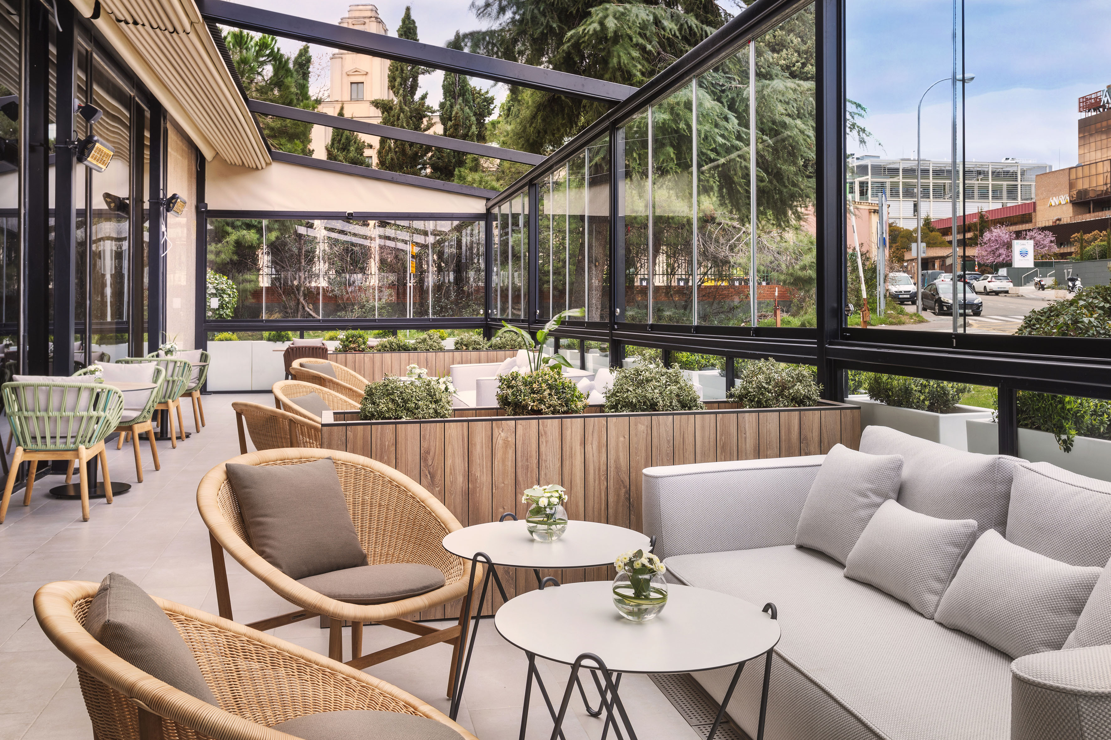 Modern glass-enclosed patio with comfortable outdoor seating and city views.