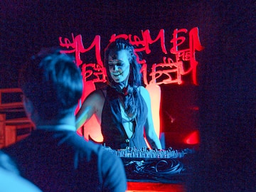 a woman with face paint on her face and a man standing behind a table