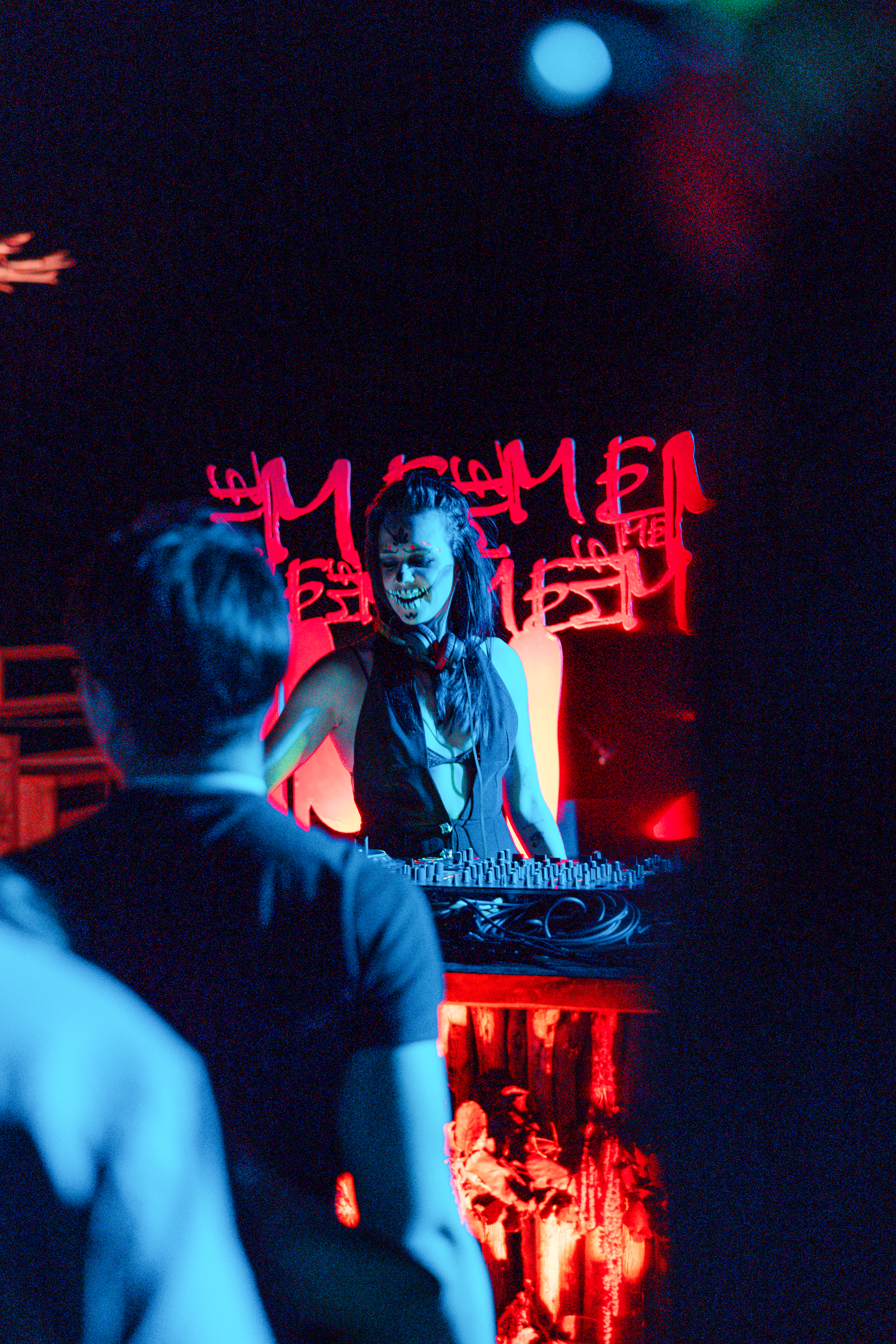 a woman with face paint on her face and a man standing behind a table