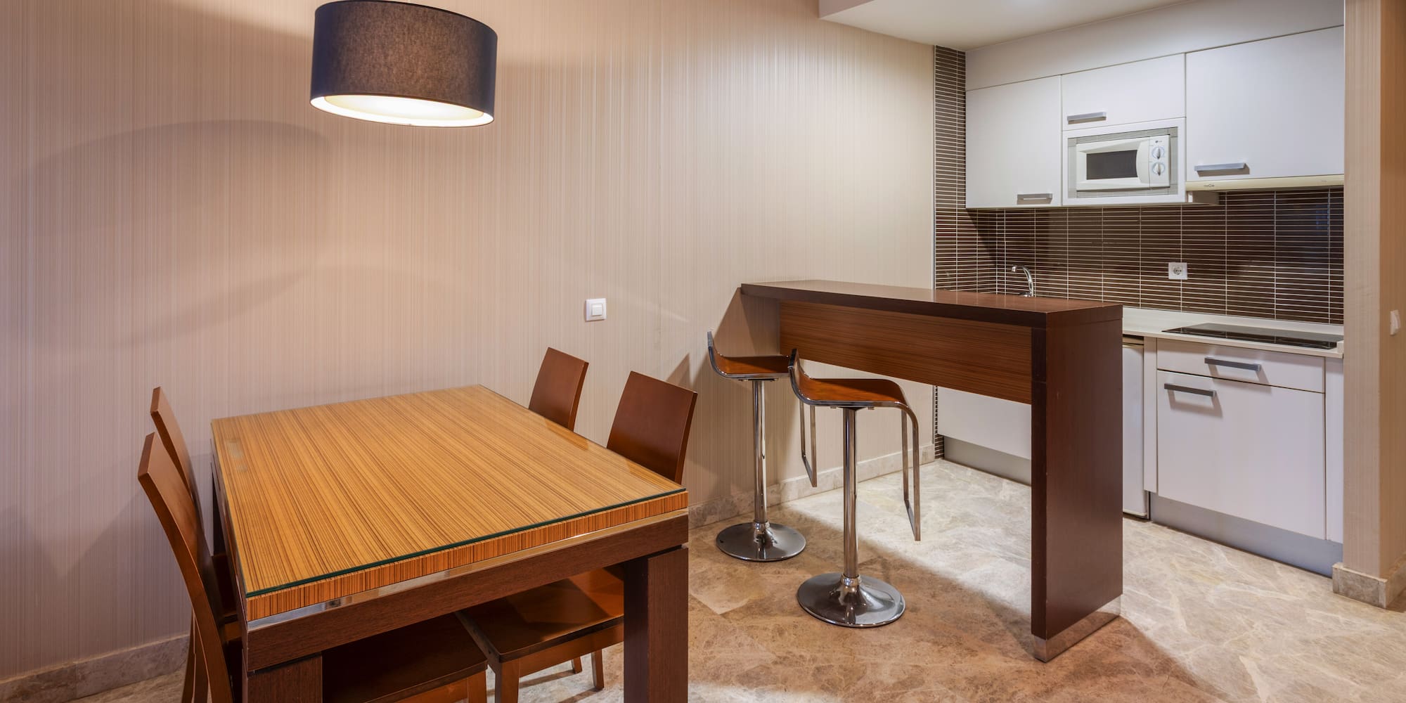 Modern kitchen and dining area with wood table, bar, and white cabinets.