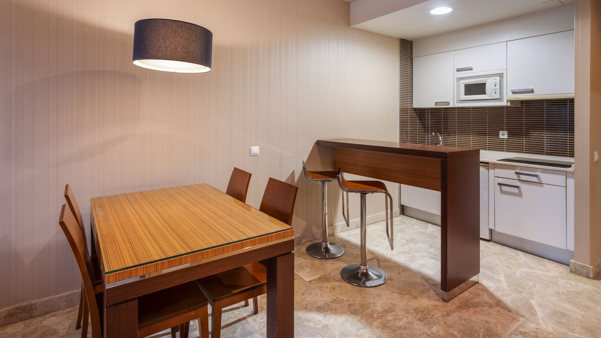 Modern kitchen and dining area with wood table, bar, and white cabinets.