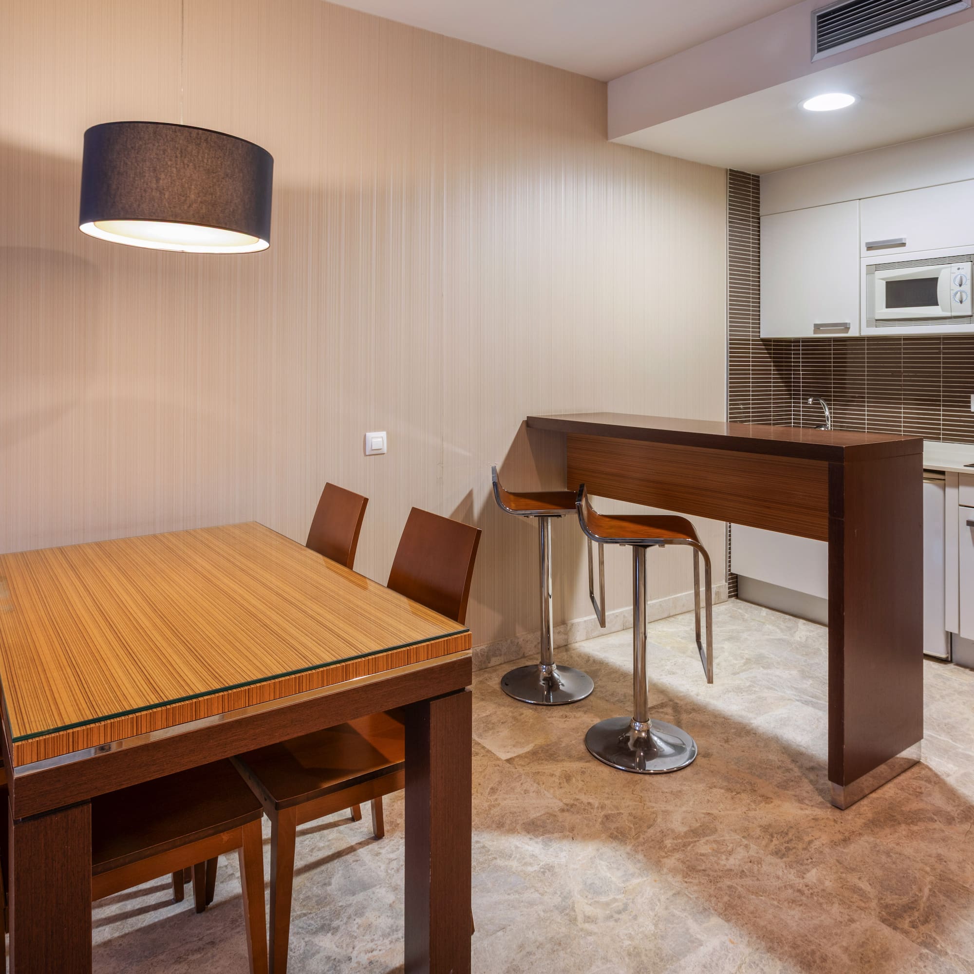 Modern kitchen and dining area with wood table, bar, and white cabinets.