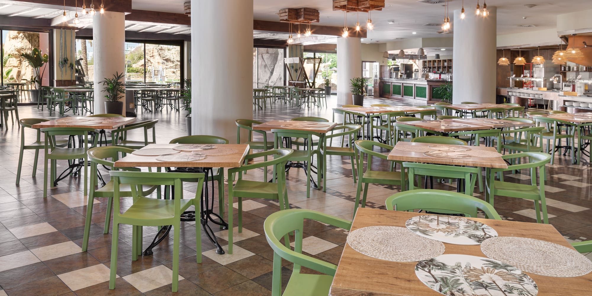Hotel dining room with green chairs, wooden tables, and buffet.