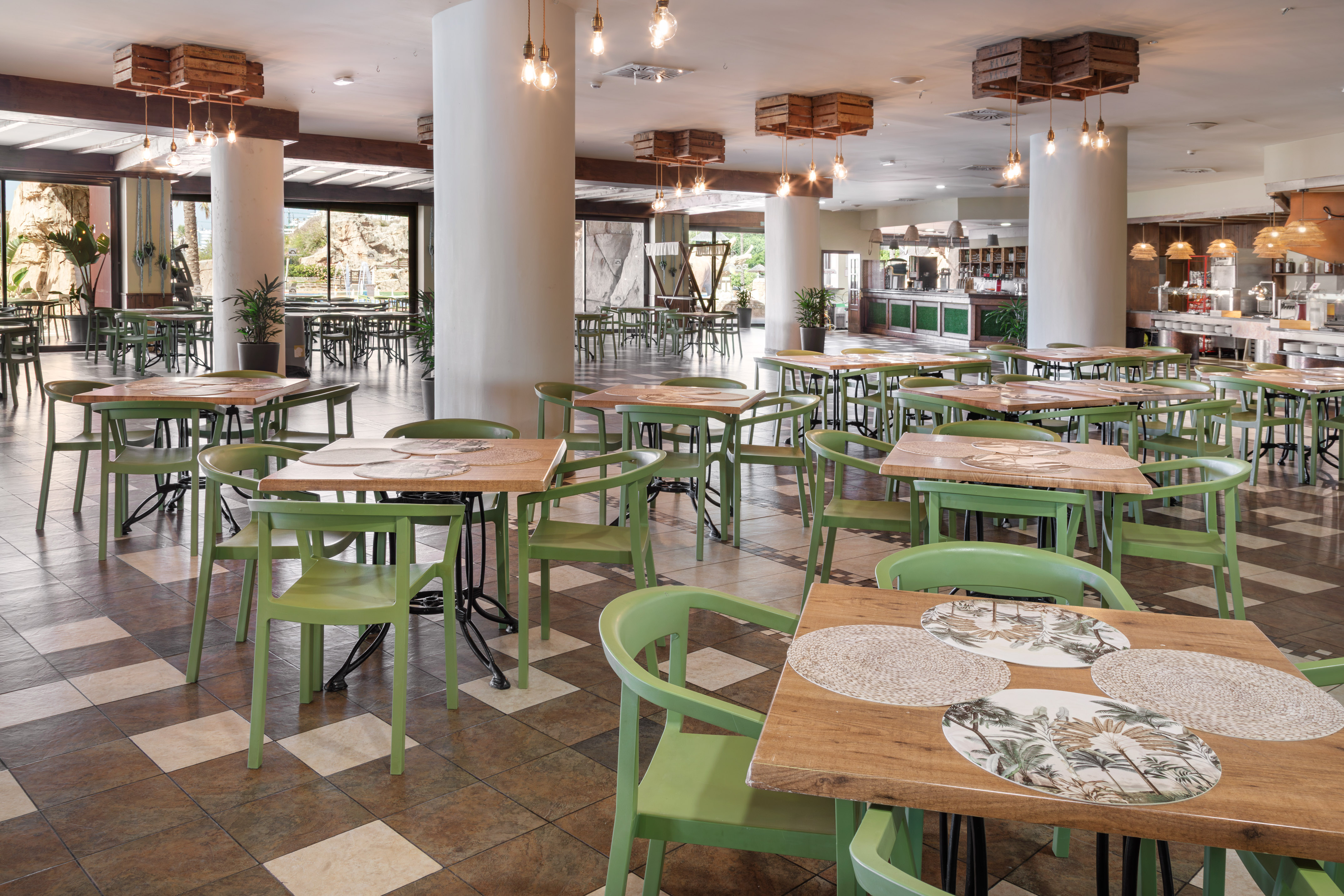 Hotel dining room with green chairs, wooden tables, and buffet.