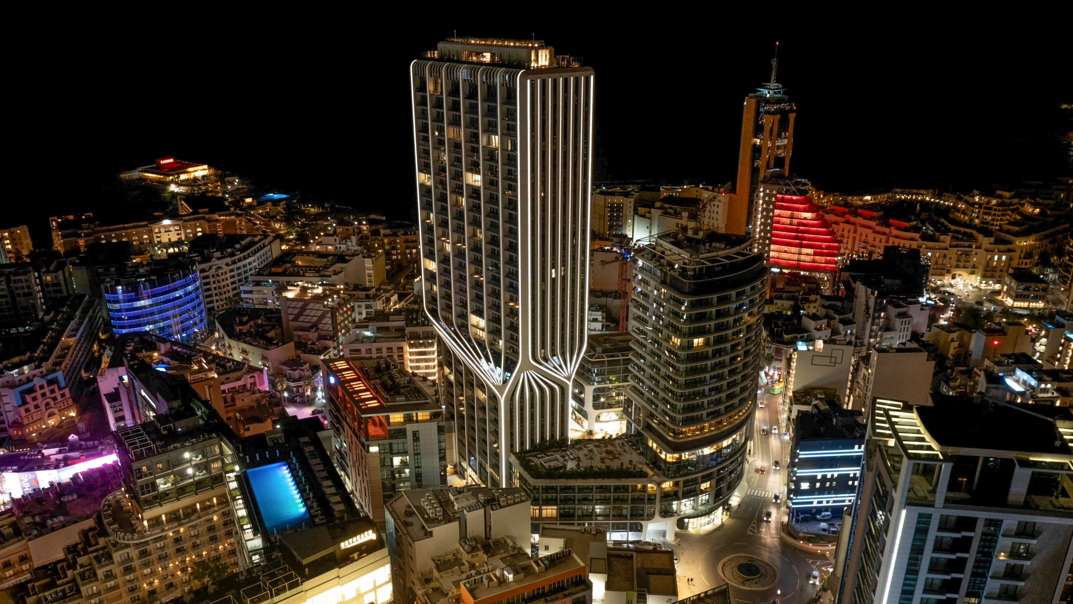 Modern illuminated skyscraper in a vibrant night cityscape.