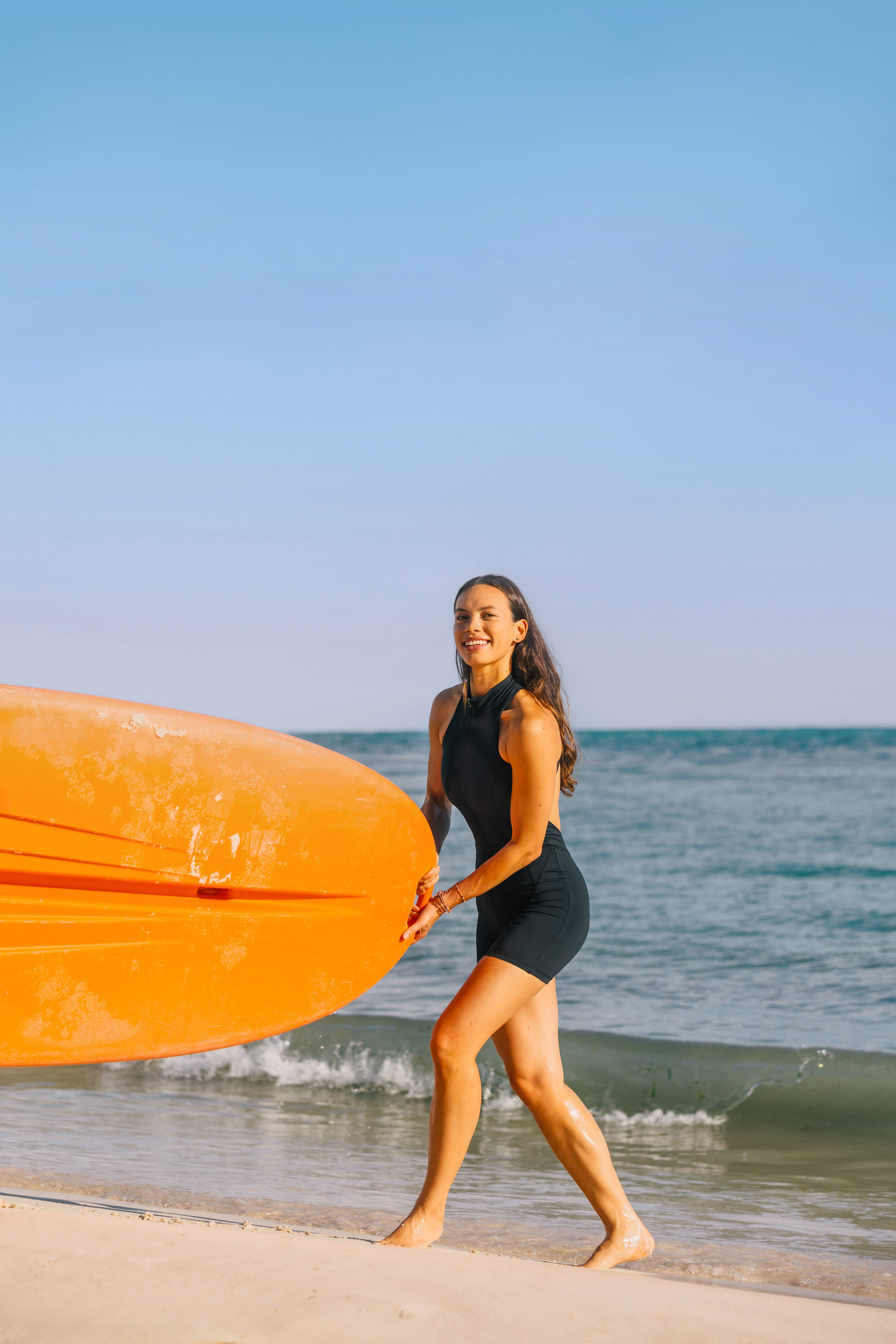 a woman holding a surfboard on a beach