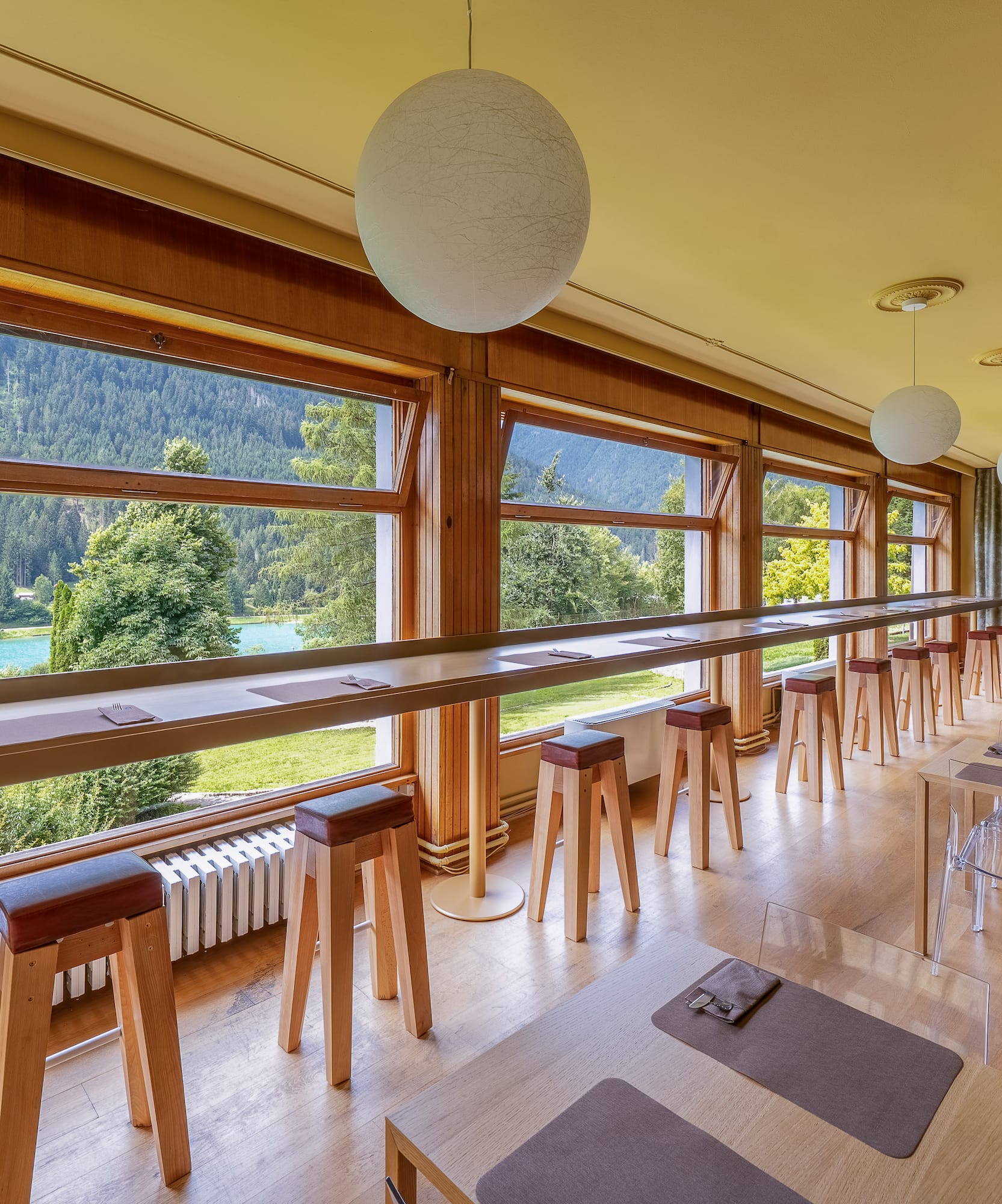 Modern cafe with scenic lake and mountain views, bar seating, and dining tables.