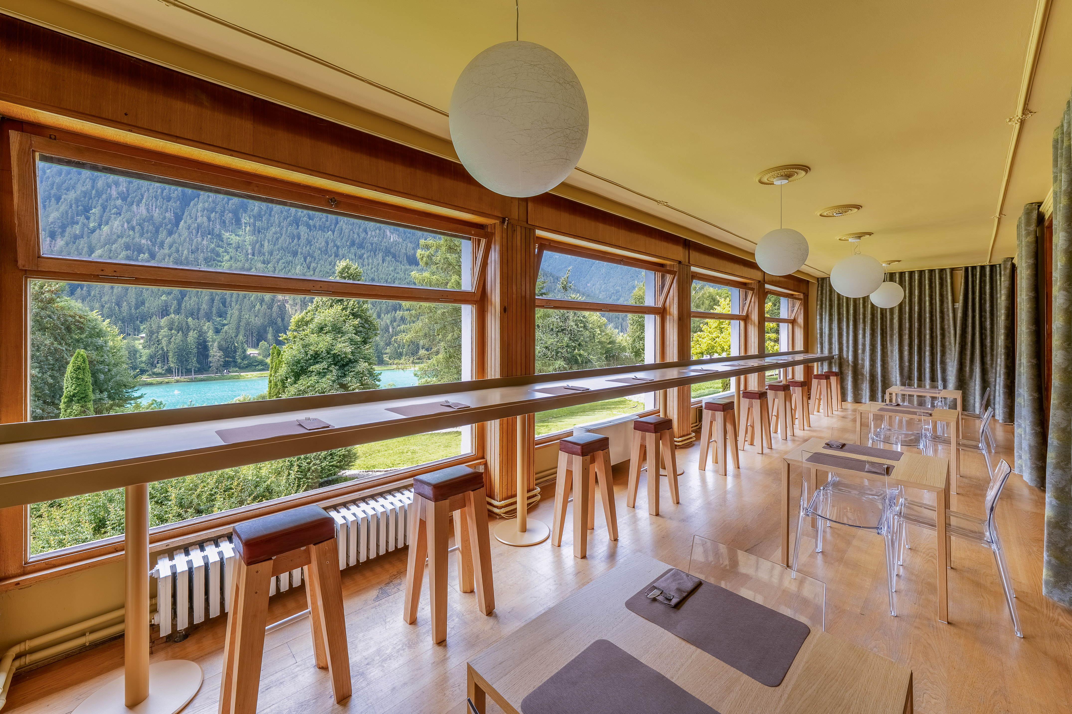 Modern cafe with scenic lake and mountain views, bar seating, and dining tables.