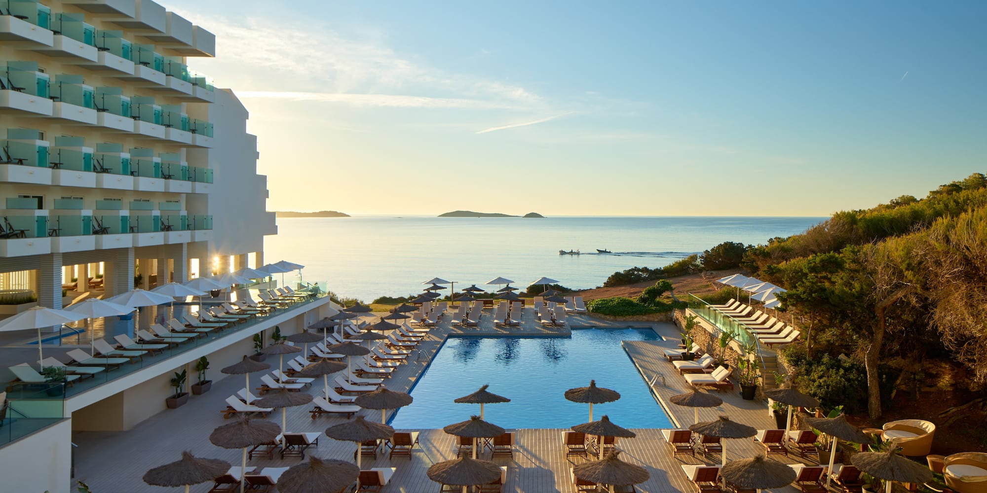 a pool with umbrellas and chairs and a building with a body of water