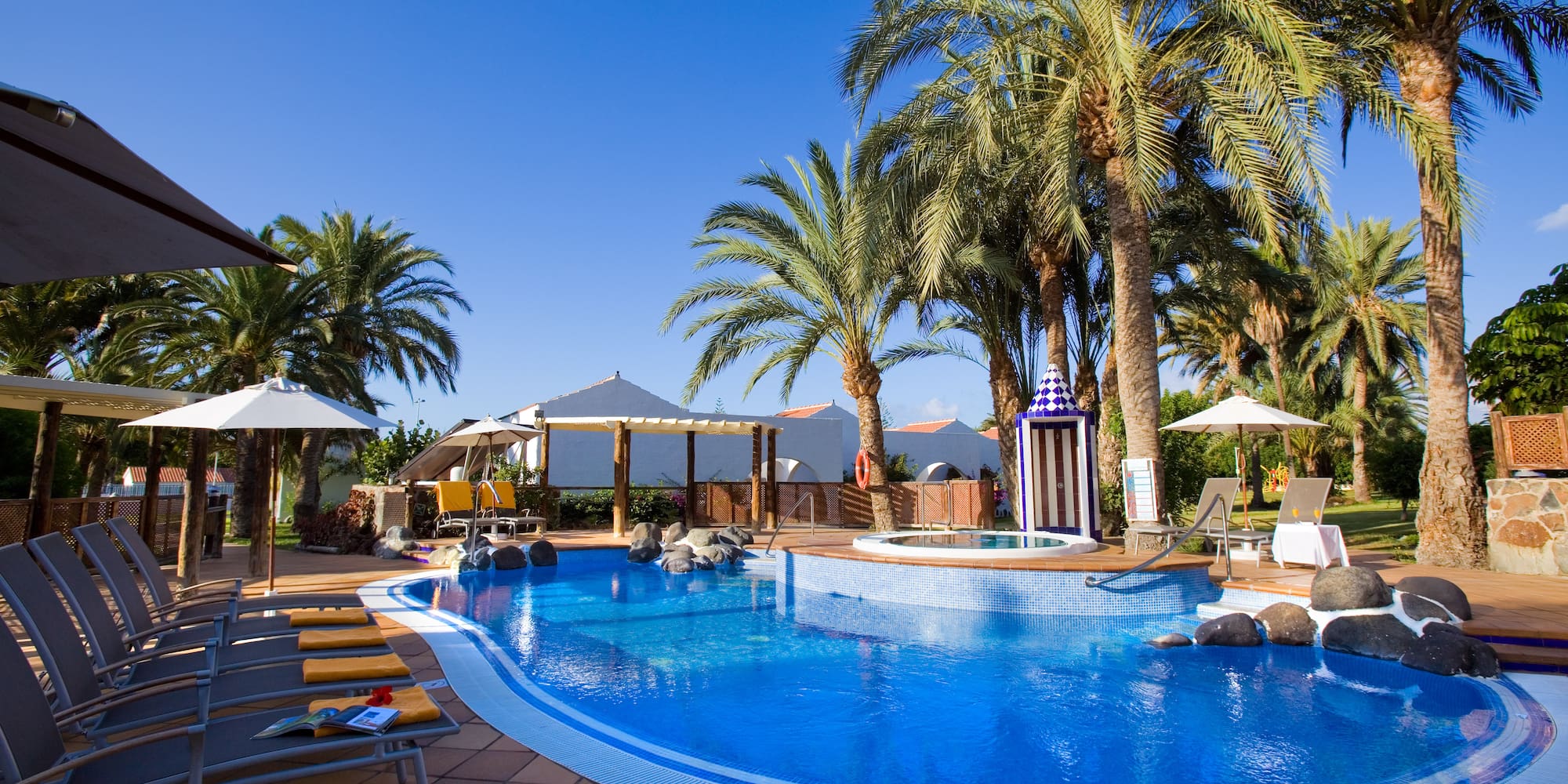 a pool with palm trees and umbrellas